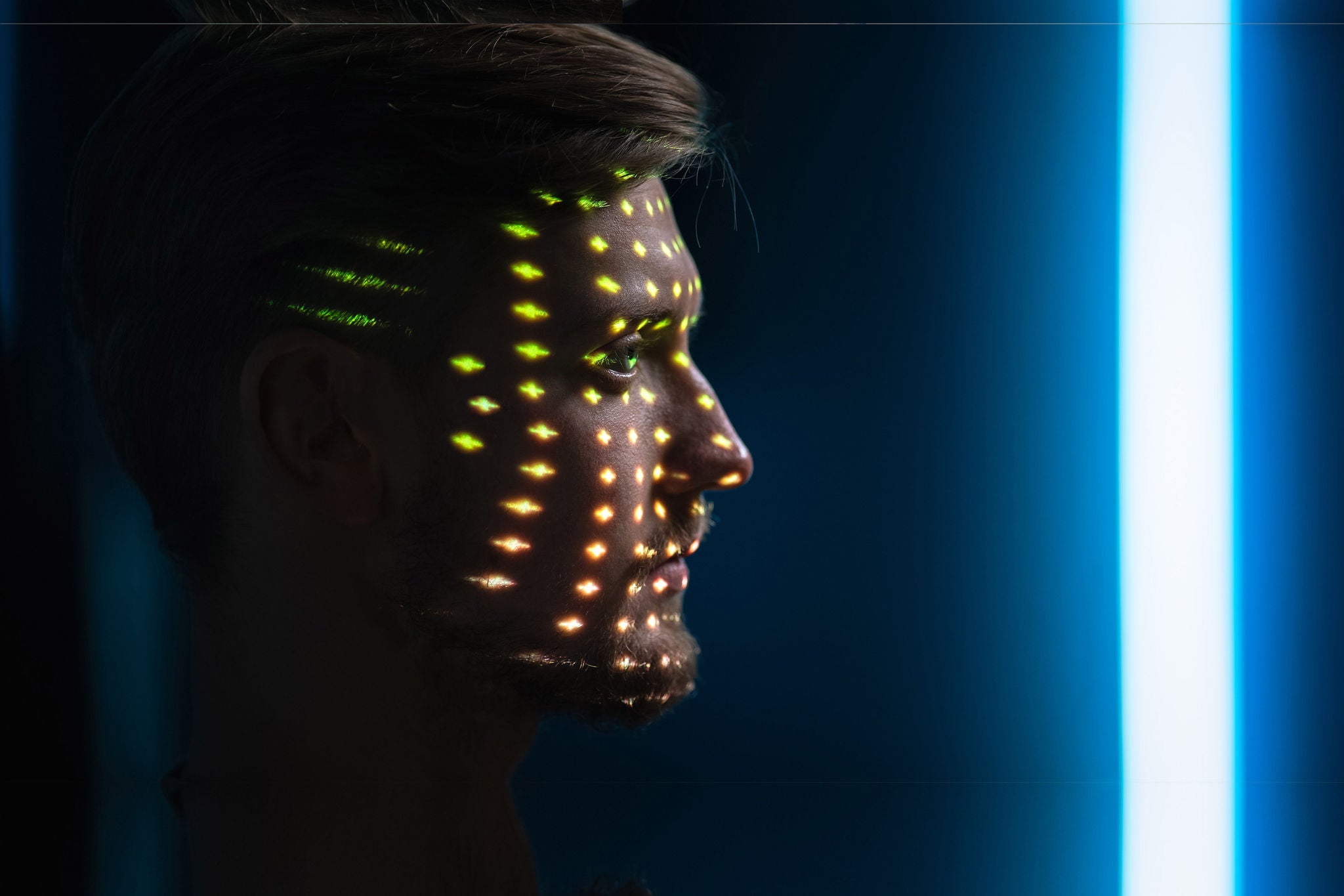 Handsome Young Caucasian Man is Identified by Biometric Facial Recognition Scanning Process. Futuristic Concept: Projector Identifies Individual by Illuminating Face by Colorful Dots and Laser