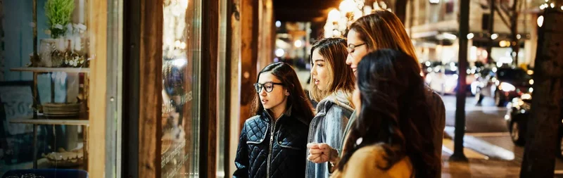 Two mature women and teenage daughters window shopping during holidays