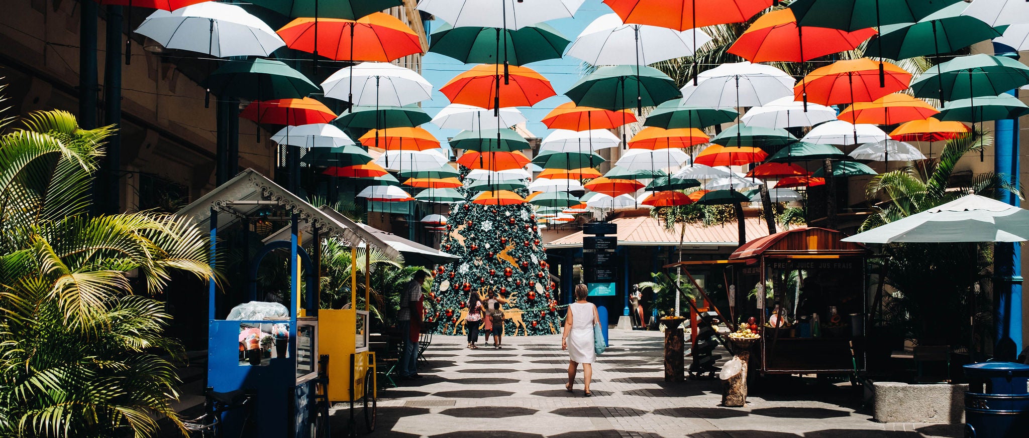 People covered with umbrellas walk along the promenade Leodan in port louis