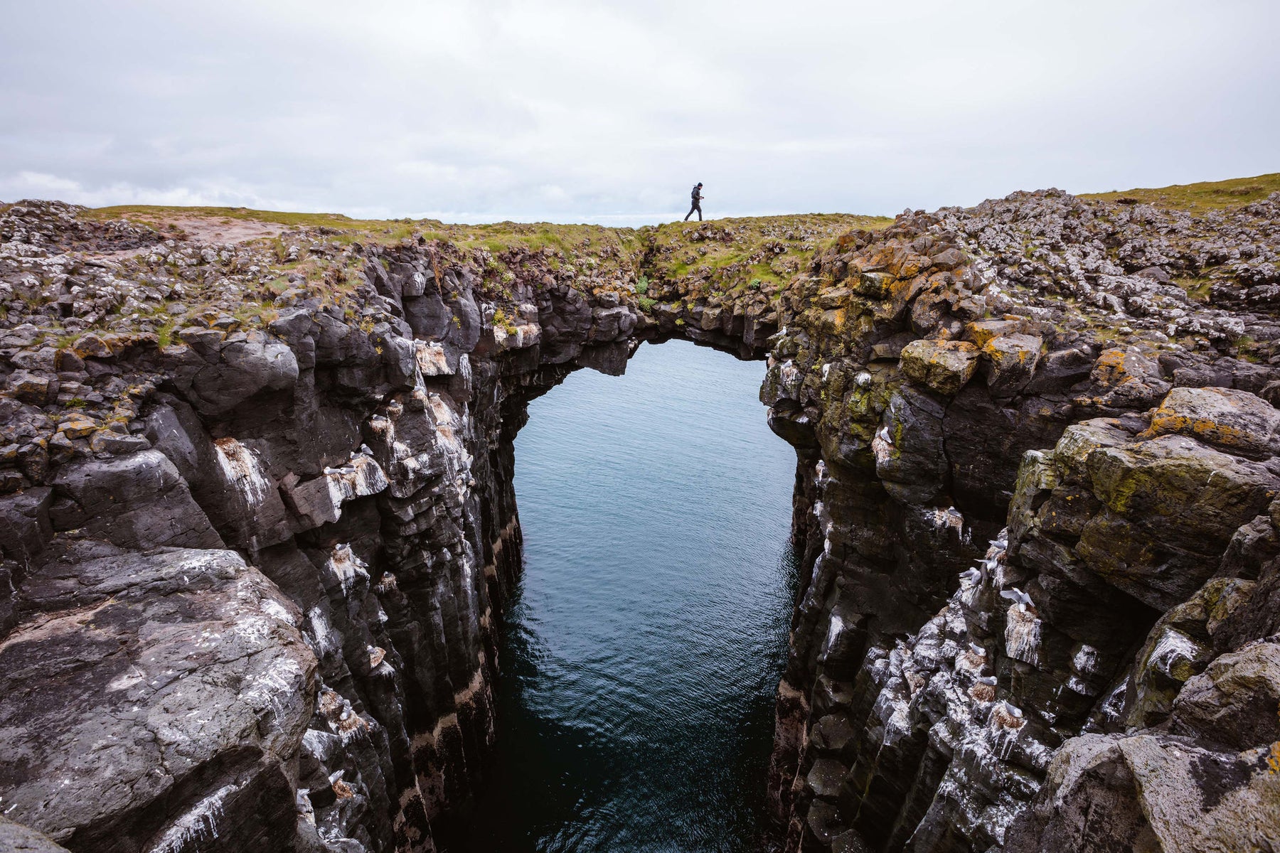 Man on top of natural rocky arch, Snaefellsnes peninsula, Iceland