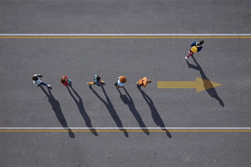 People walking in line on road with one person walking off