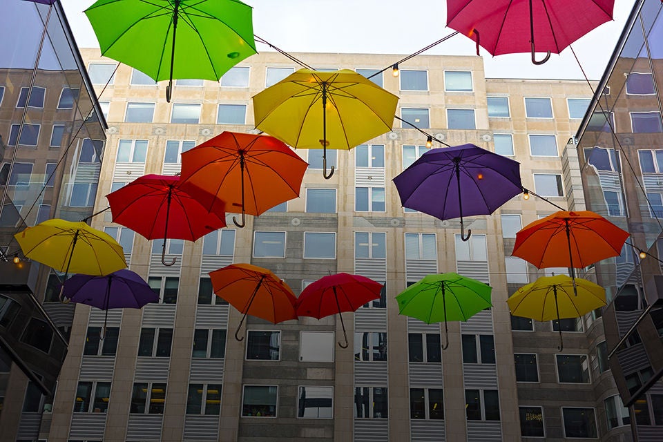 Colorful umbrellas flying between two buildings in Washington DC downtown, USA. Cozy friendly atmosphere on the street with shops and restaurants in US capital.