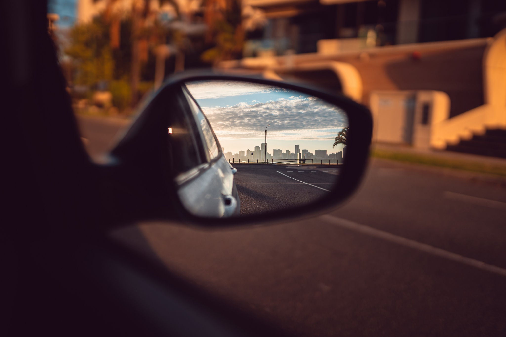 ey skyline in the sideview mirror of a car