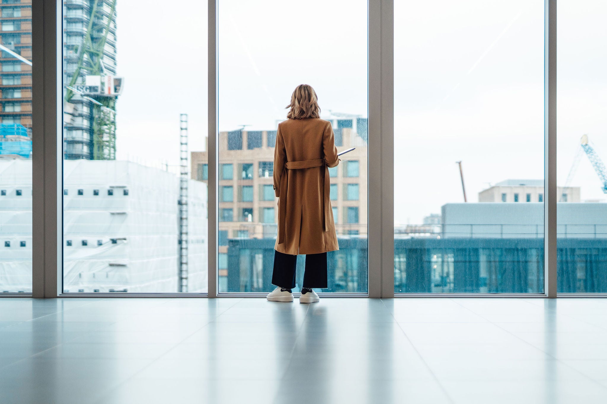 Back view of businesswoman standing and looking through window in conference room.