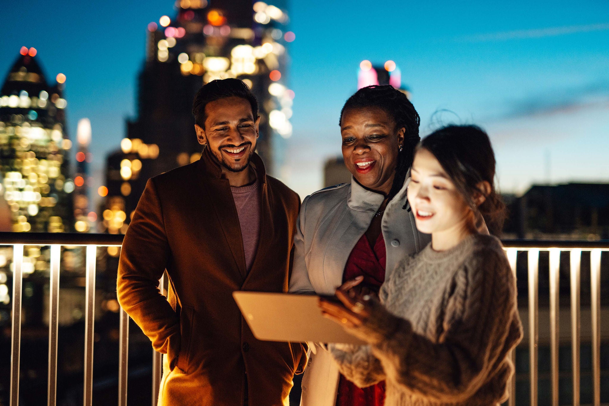 Coworkers working and talking at rooftop against London cityscape at night