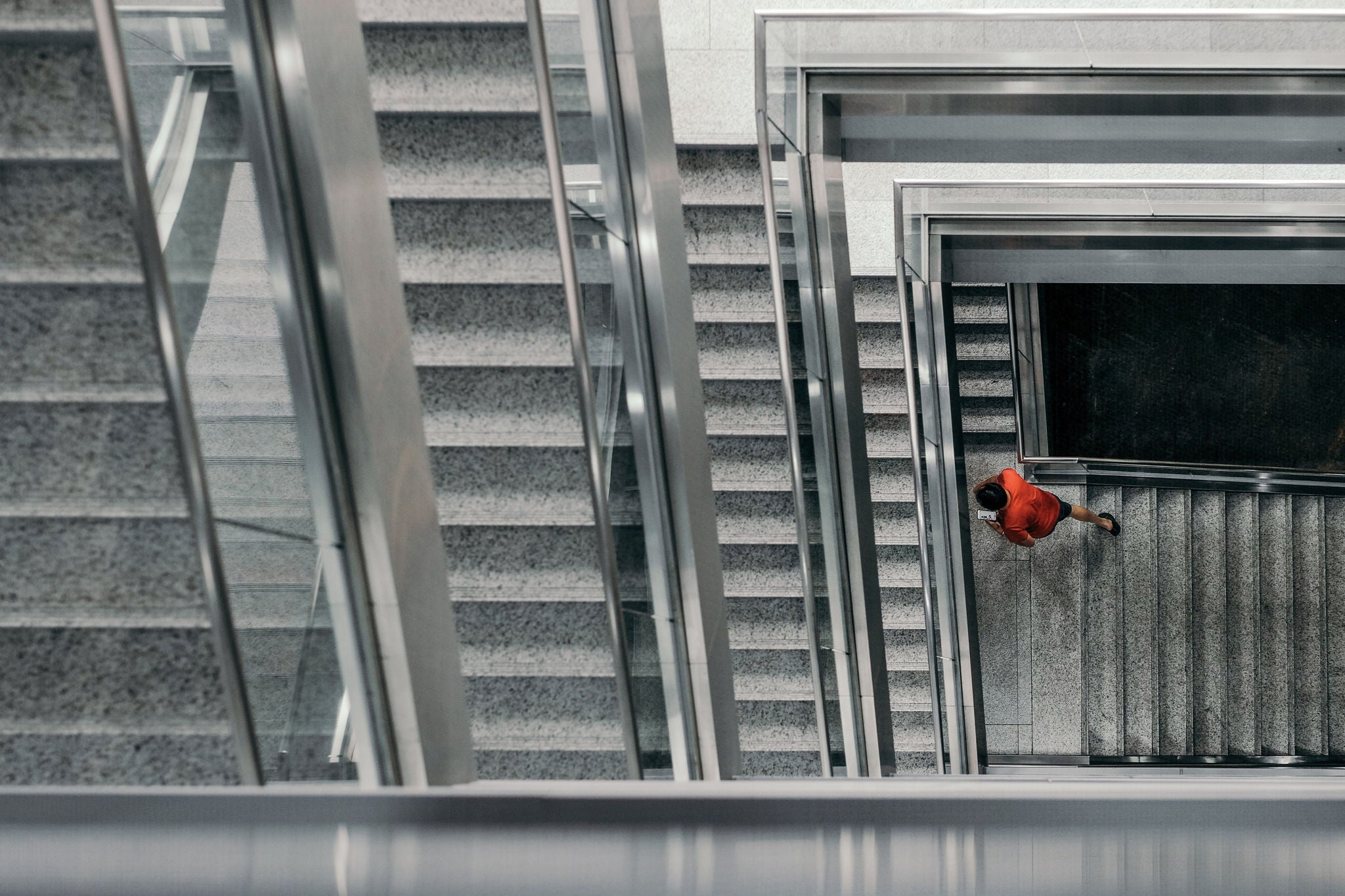 High angle view of man in red shirt walking up the staircase