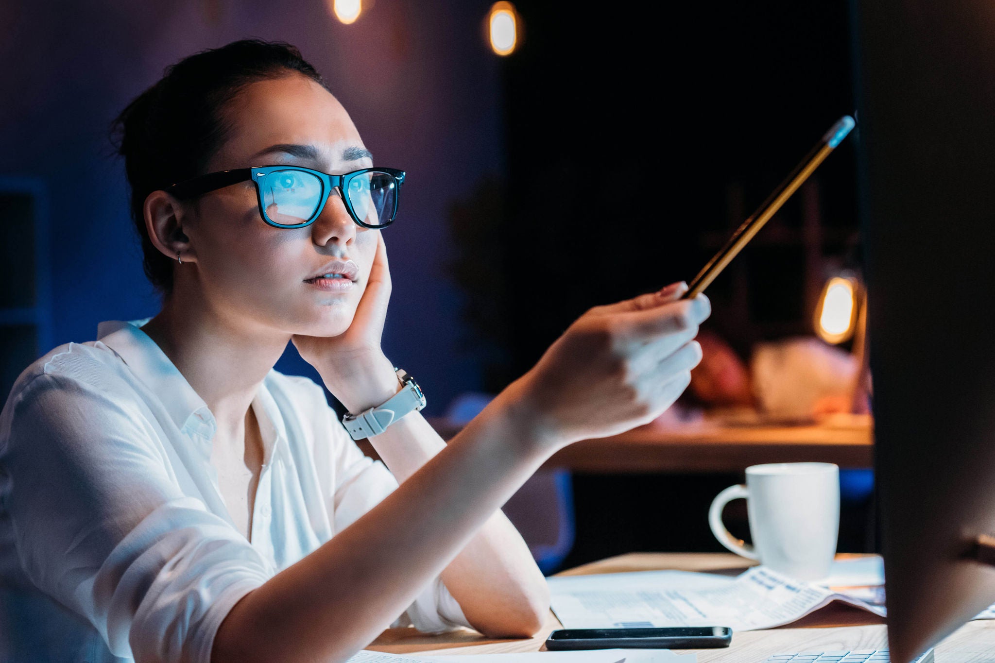 A focused woman wearing glasses with a blue light reflection on the lenses