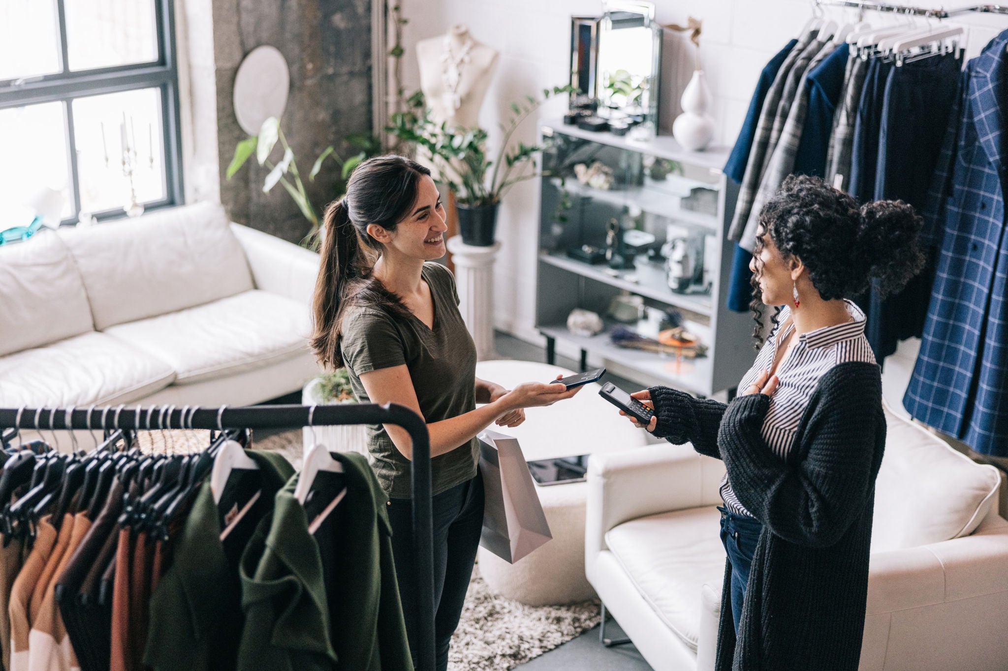 EY - Femme d’Amérique latine effectuant un paiement mobile dans une boutique moderne