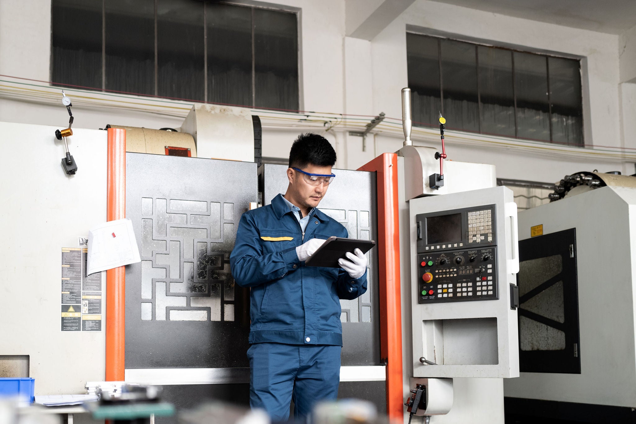 Engineer using computer in front of CNC machine tool