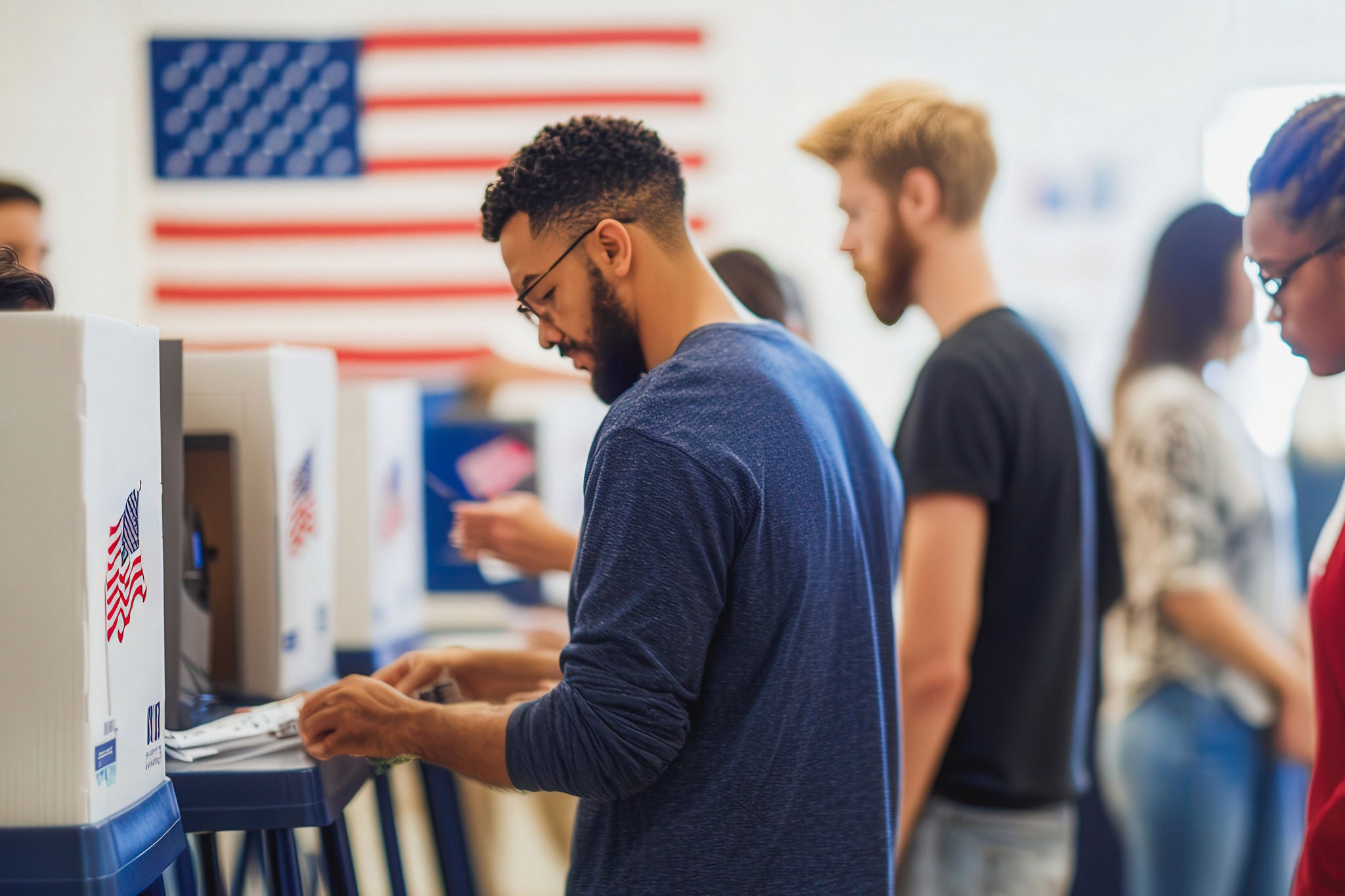 A group of people are voting in a polling station. A man is filling out a ballot. Scene is serious and focused