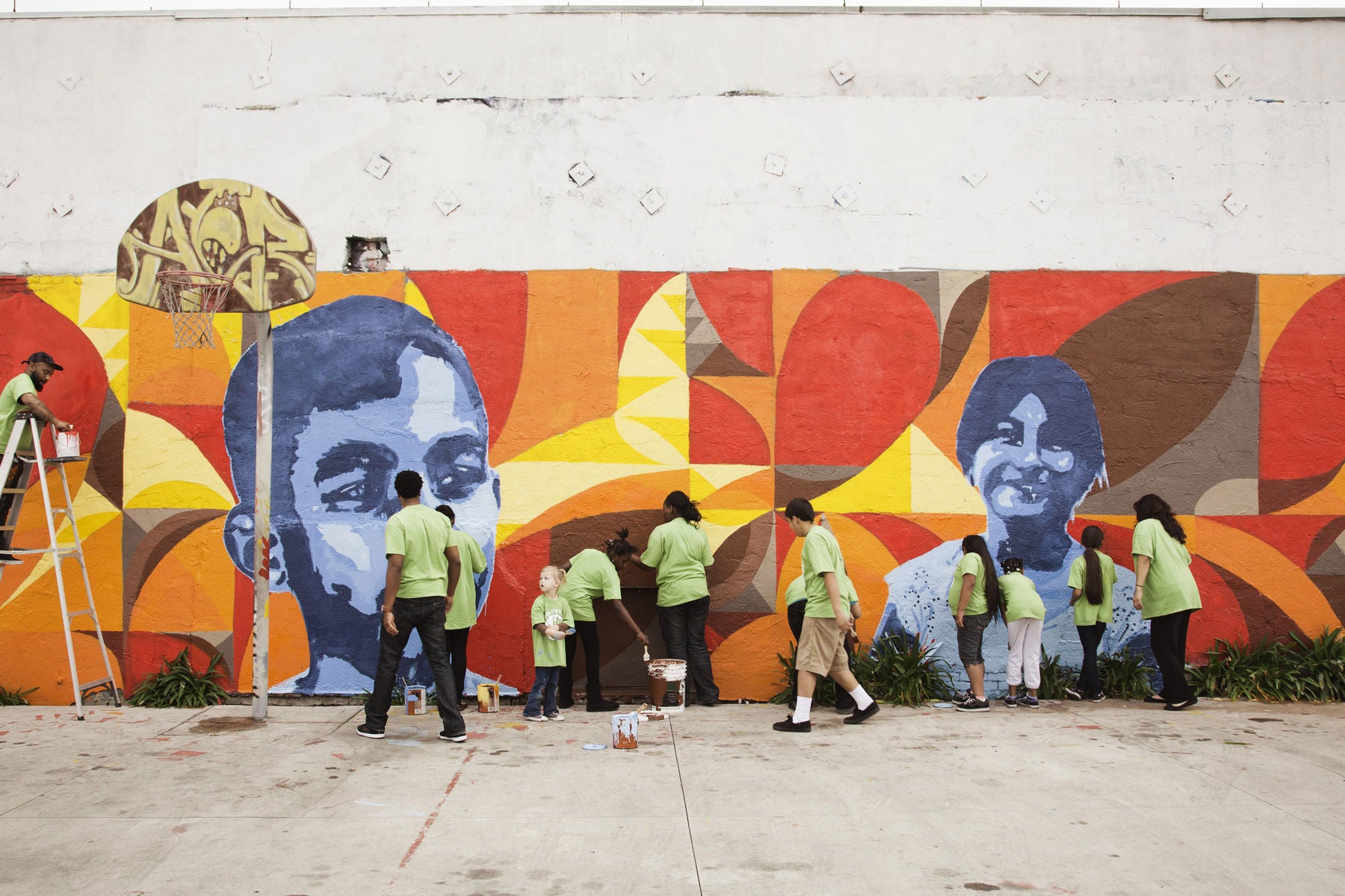 A group of people painting a mural on a commmunity wall