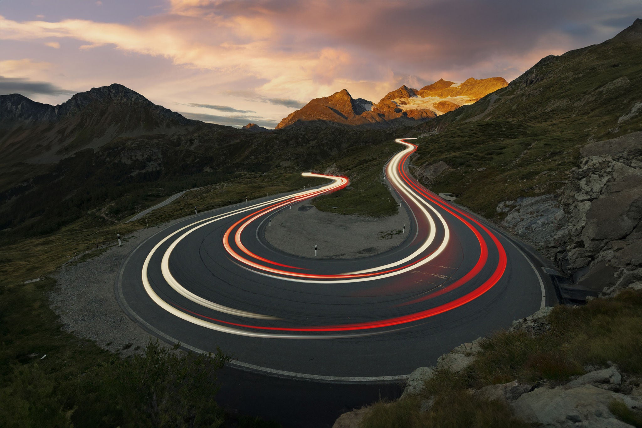 Lights of car trails on Bernina Pass mountain road at sunrise, Val Poschiavo, canton of Graubunden, Switzerland