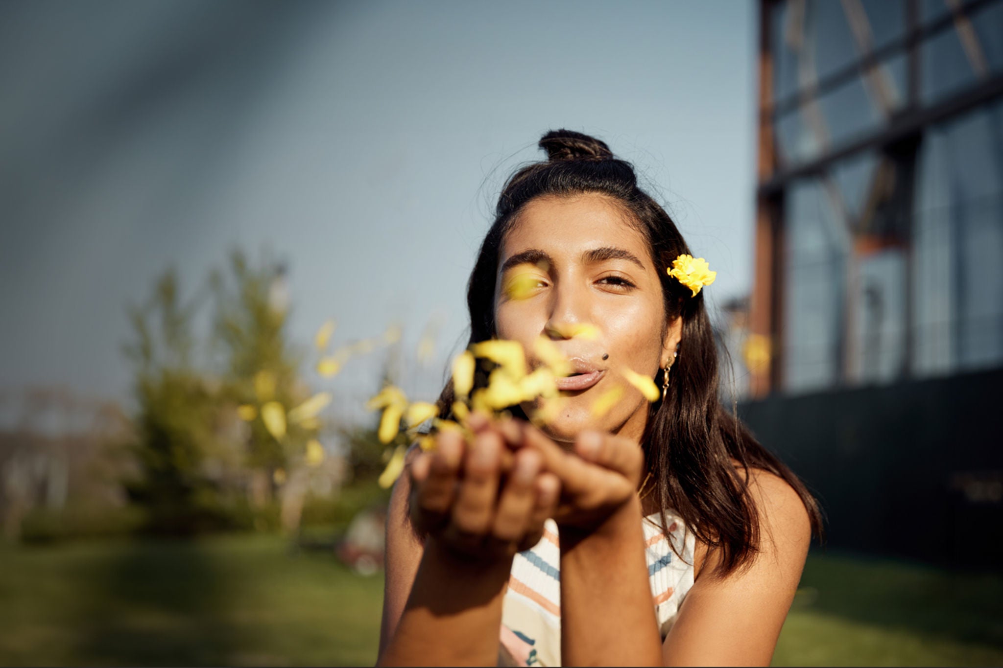 A woman blows yellow flower petals from her hands