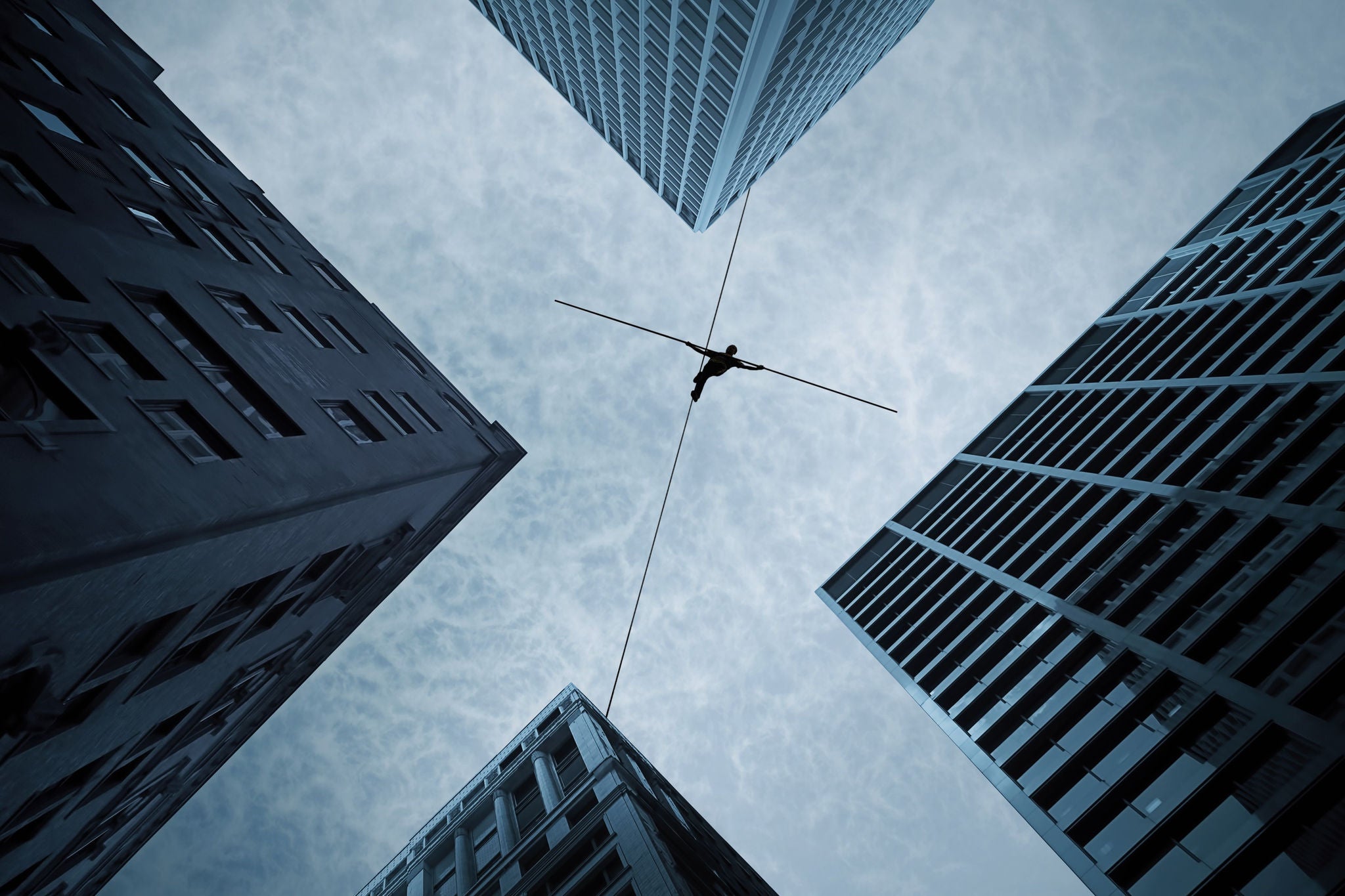 Man balancing on a slackline between skyscrapers