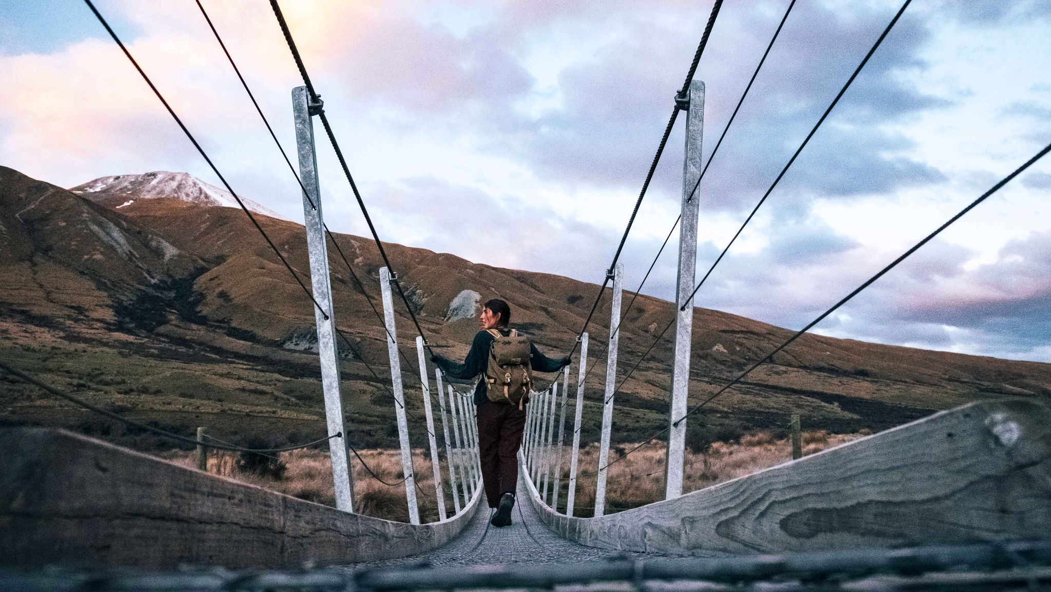 Tourist crossing a hanging footbridge in South Island, New Zealand.