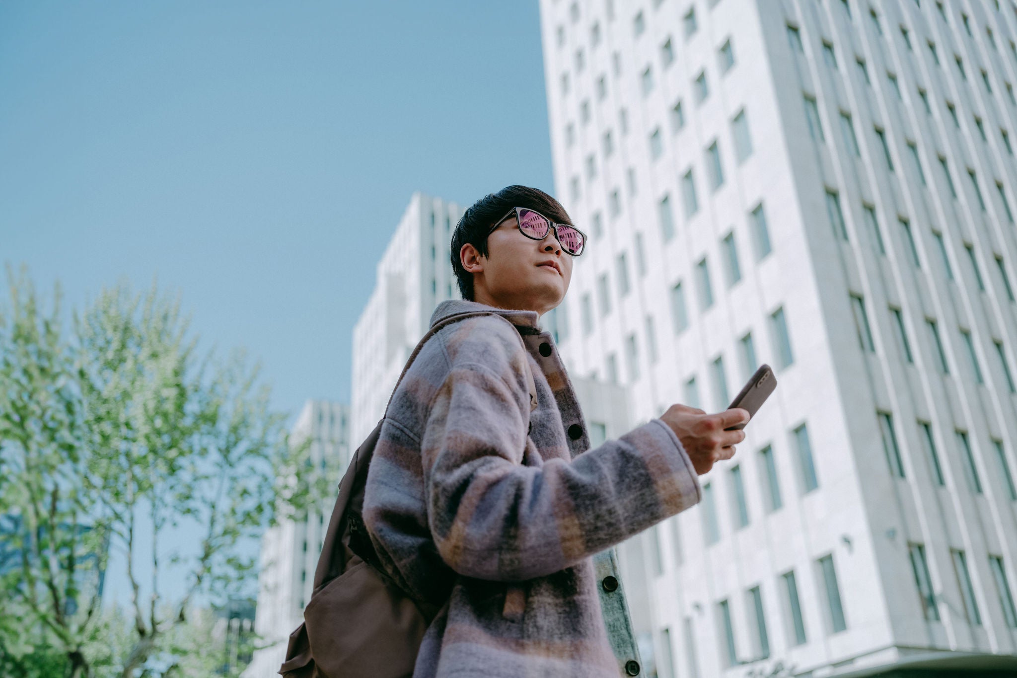 Man using smartphone while standing next to office building