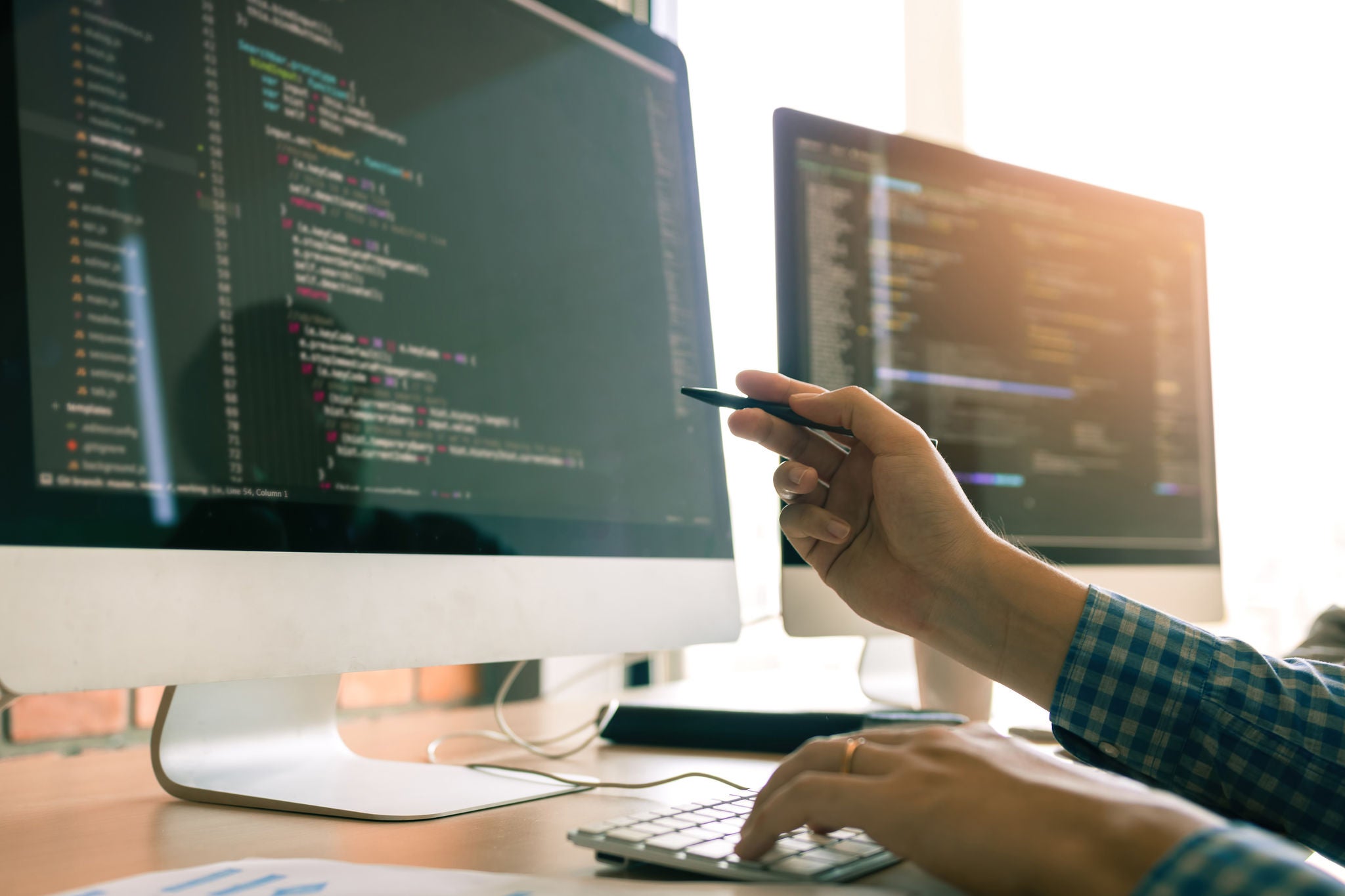 Developing programming working in a software engineers code tech applications on desk in office room.