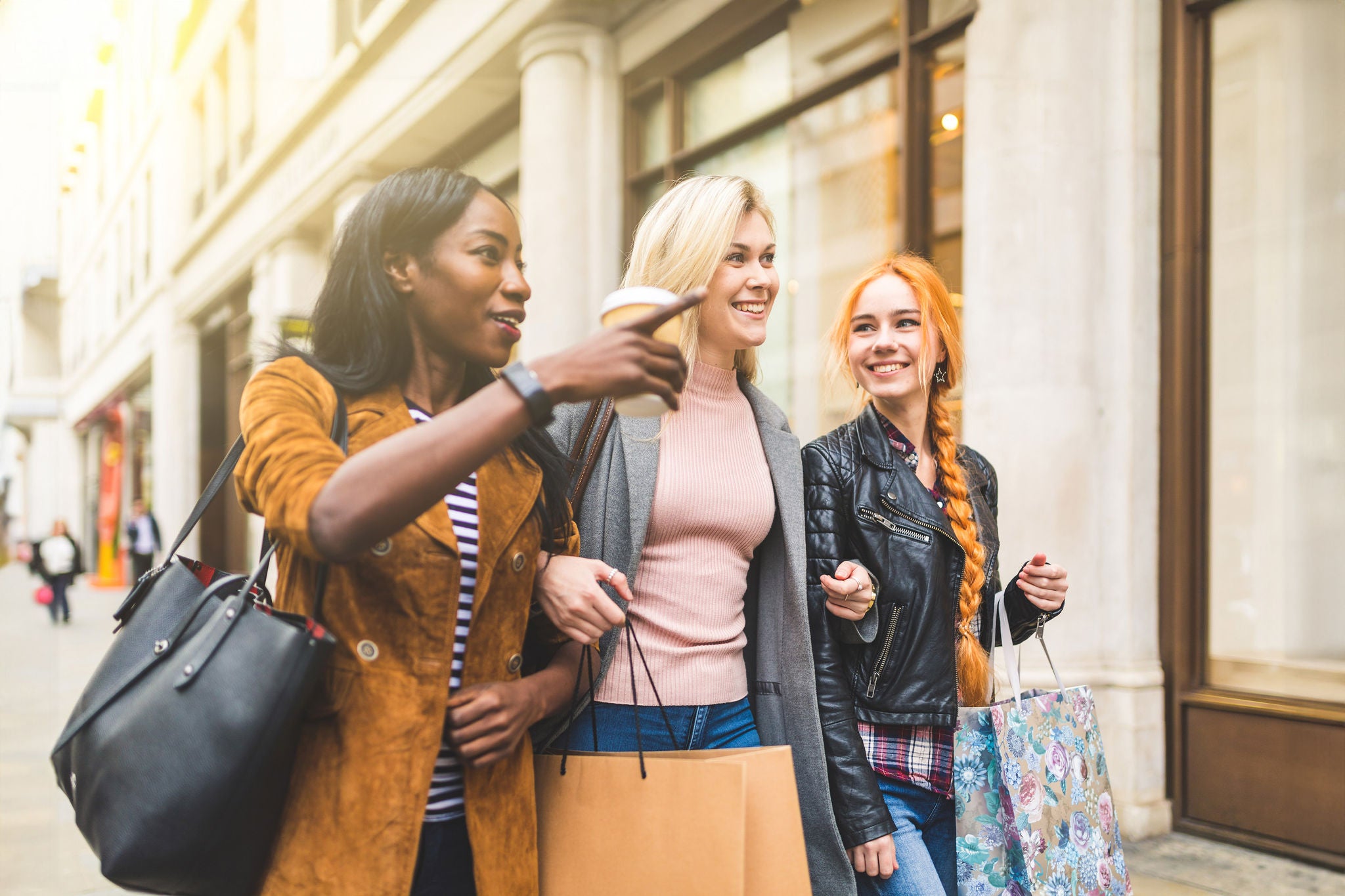 Multiracial group of women shopping and walking in London. Three girls, mixed race group, having fun in the city while shopping. Best friends sharing happy moments together