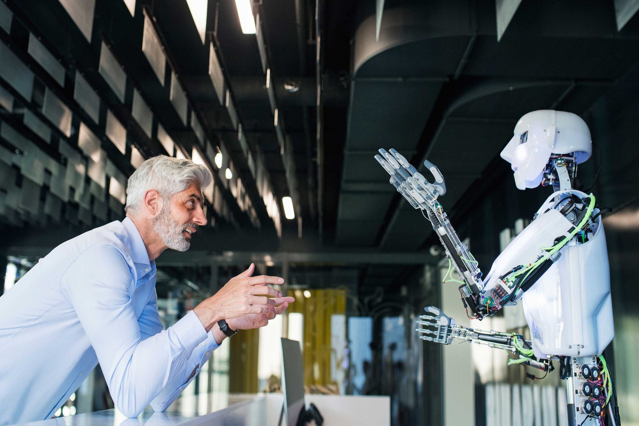 Mature businessman or a scientist with gray hair with a robot.