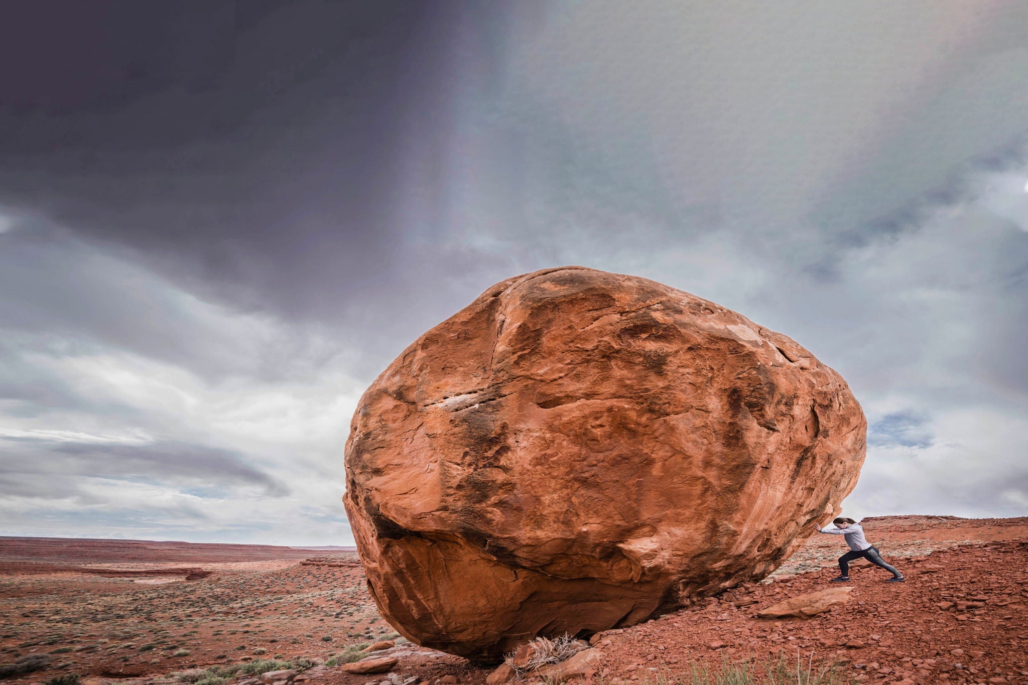 Ey caucasian man pushing boulder in desert landscape