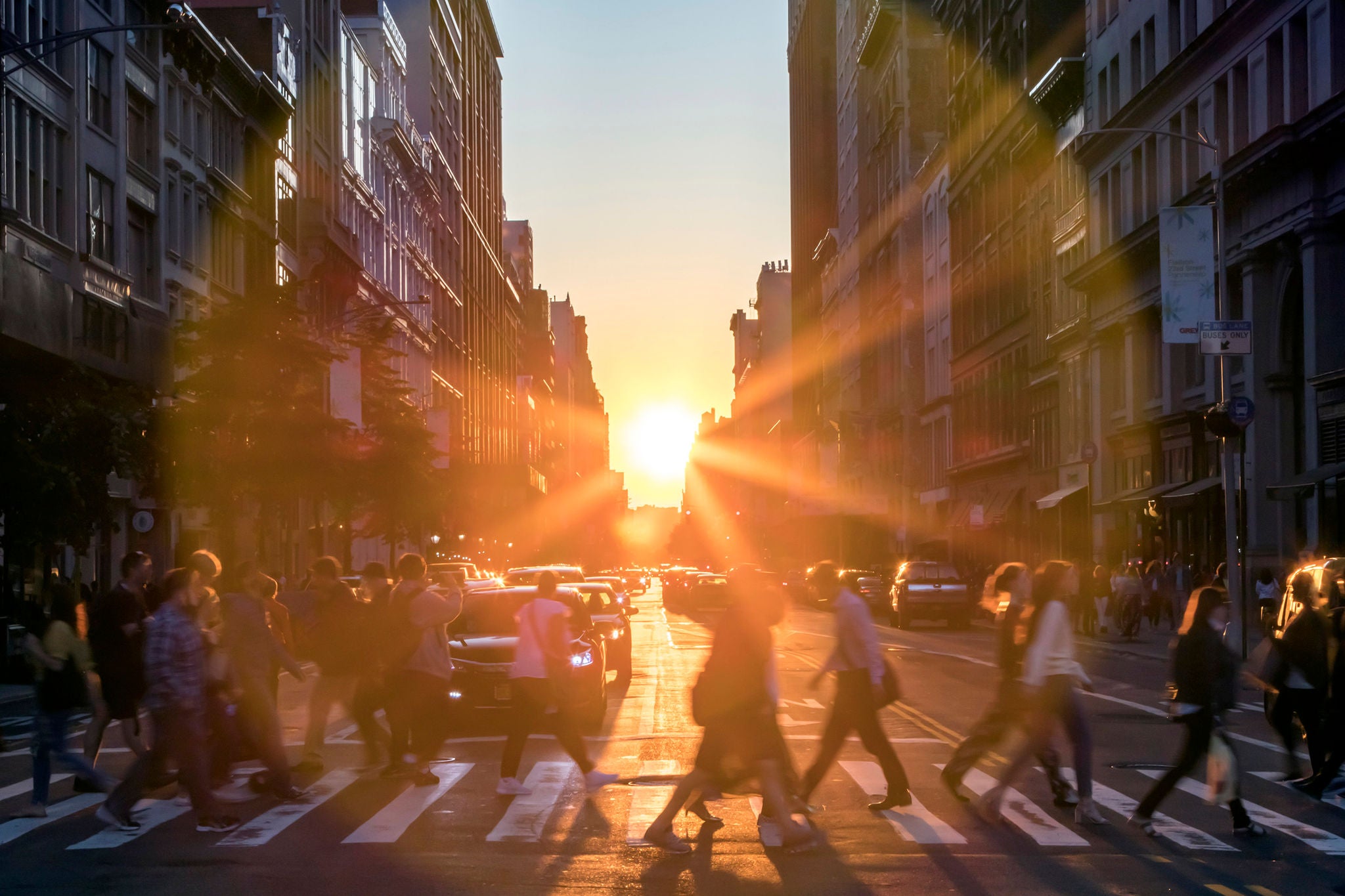 Sunlight shines over buildings and people in street