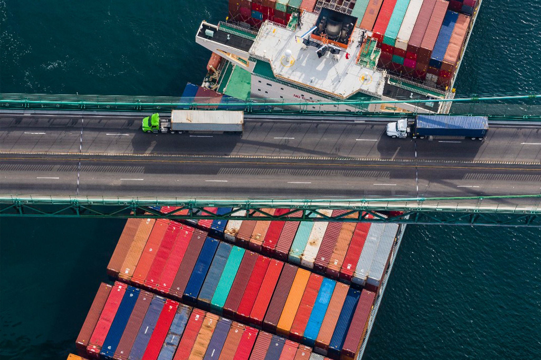 Aerial shot of two trucks driving across a bridge