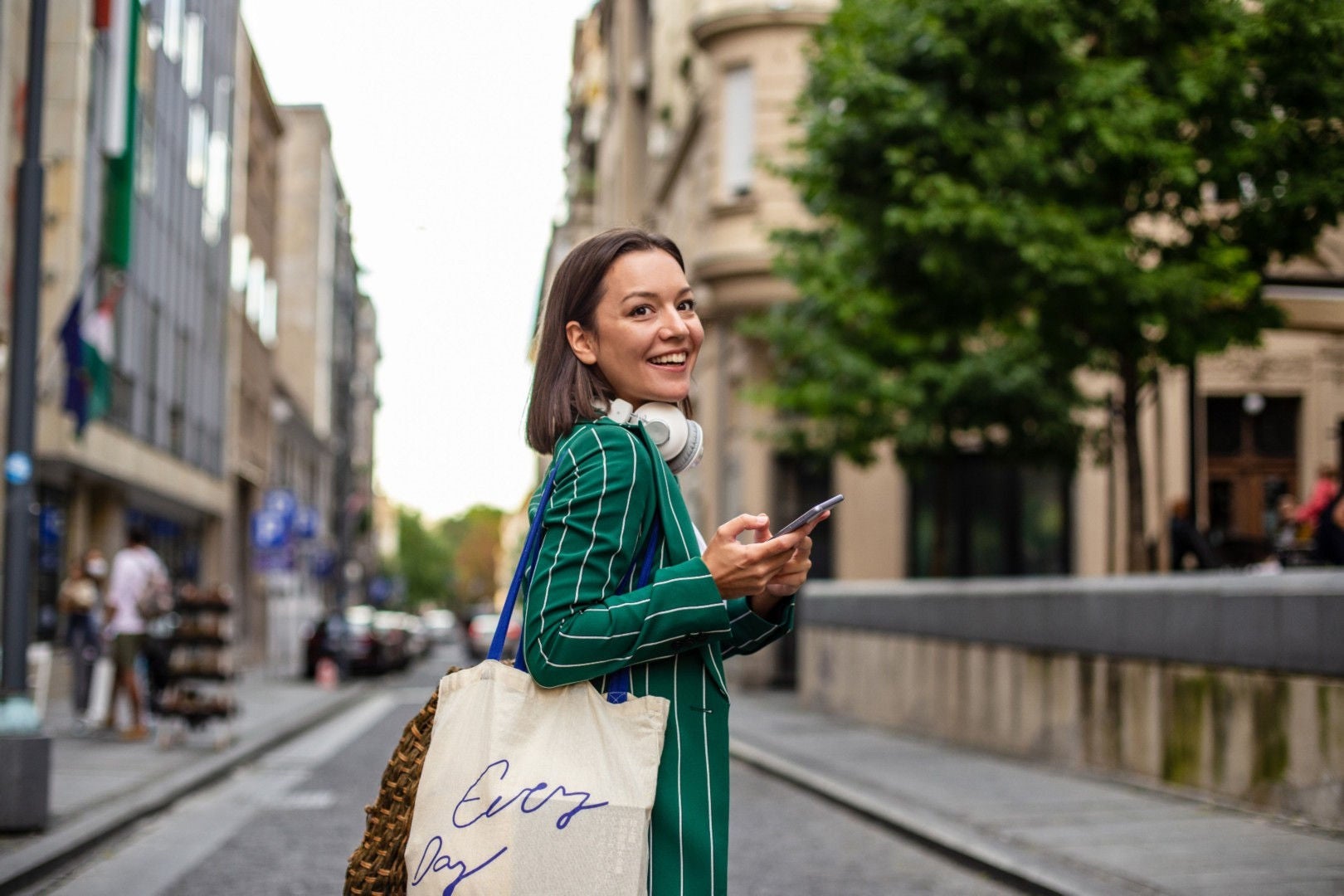 A lady is standing middle of the road and holding mobile