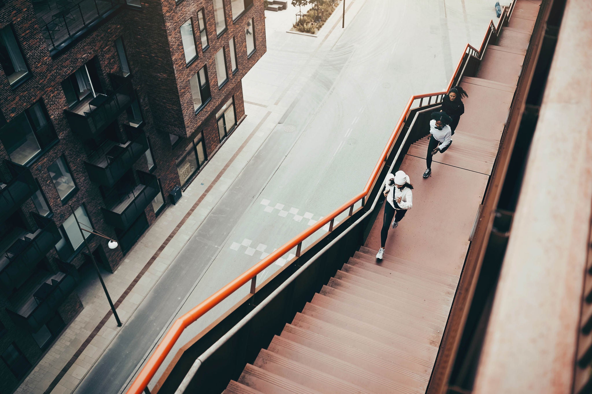 High angle view of a diverse group of women in sportswear running together up some stairs in the city