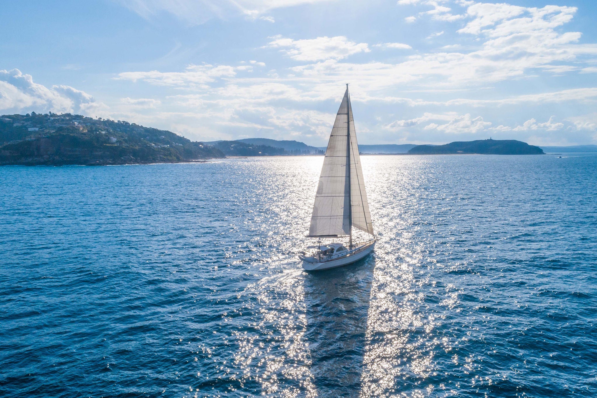 Sailboat sailing along the coast on a sunnyday