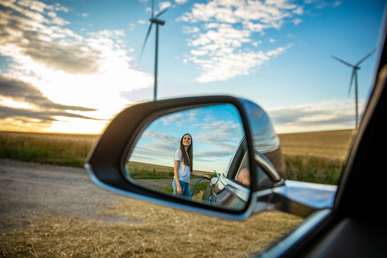 Reflexion einer Dame im Rückspiegel in einem Windfeld