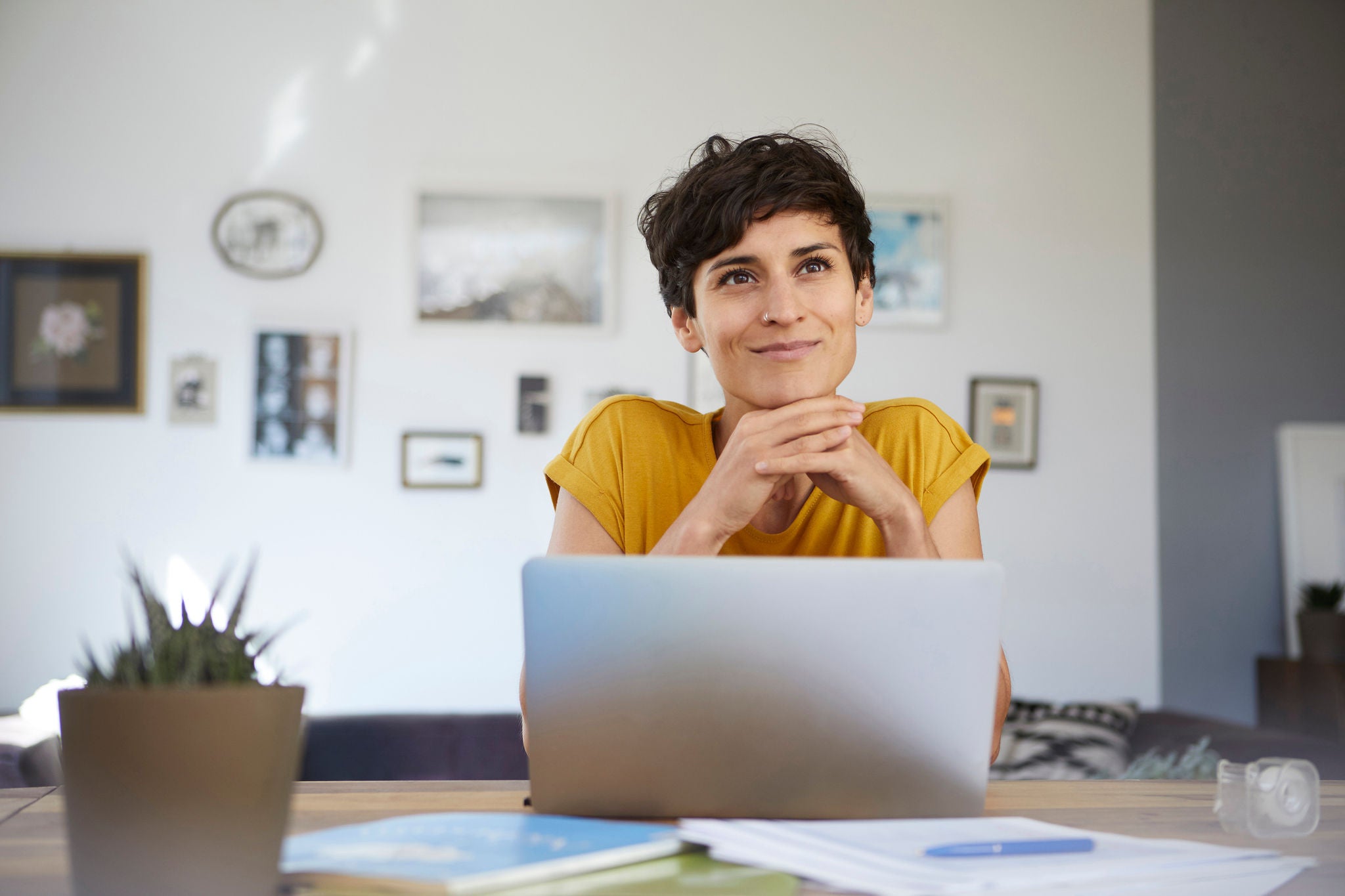 Portræt af smilende kvinde med lap-top der sidder i sin stue.