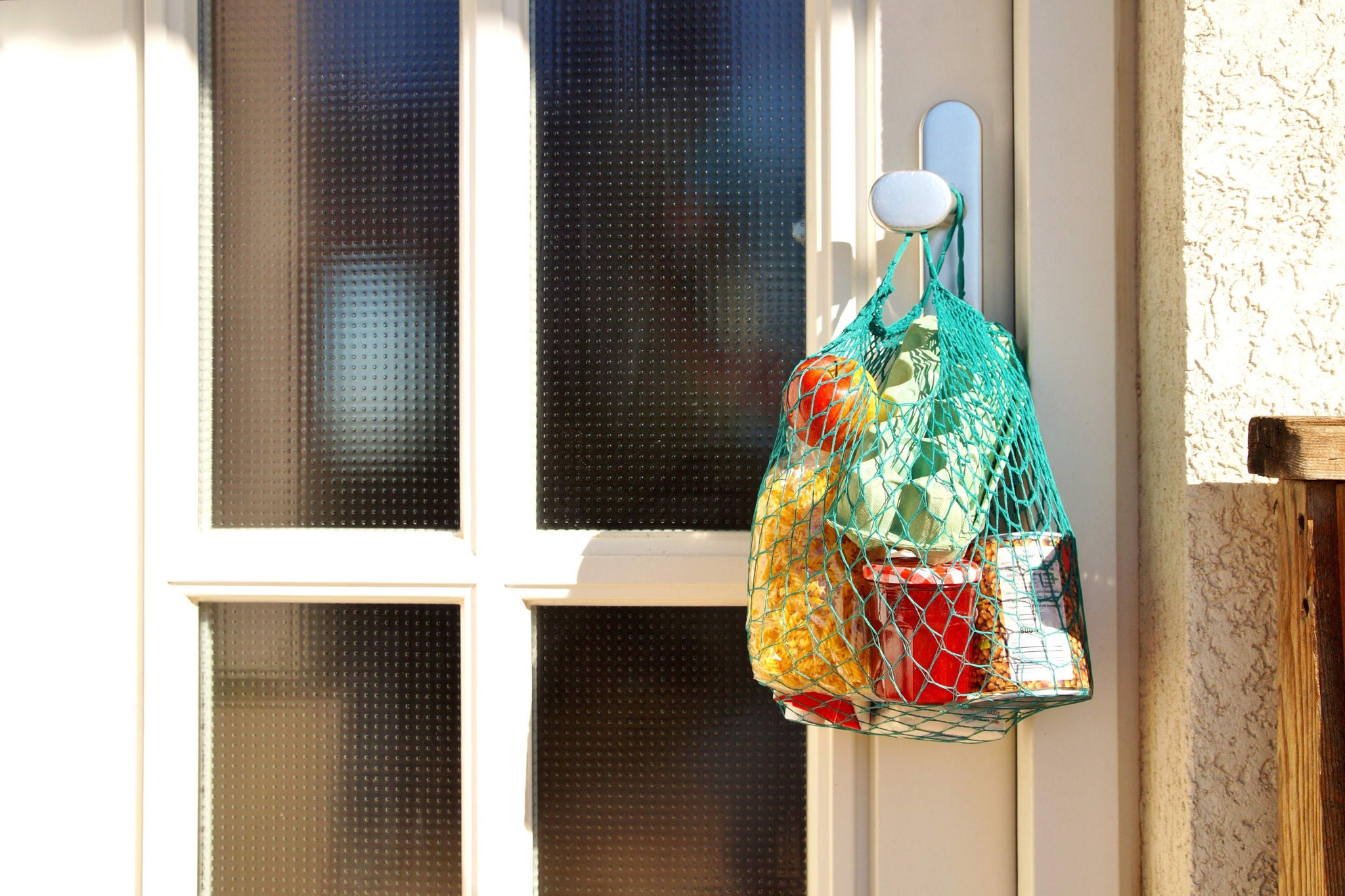 delivery during the quarantine. Shopping bag with Merchandise, goods and food is hanging at the front door