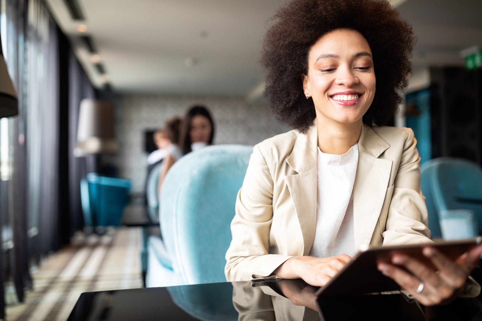 Happy businesswoman using tablet computer in coffee shop