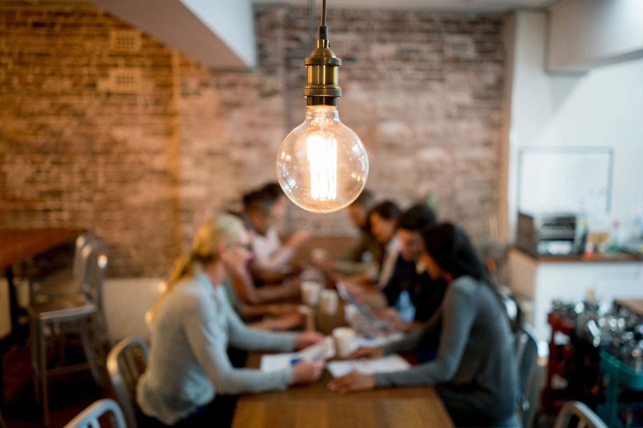 Group of business people brainstorming at a creative office and a light bulb in the foreground