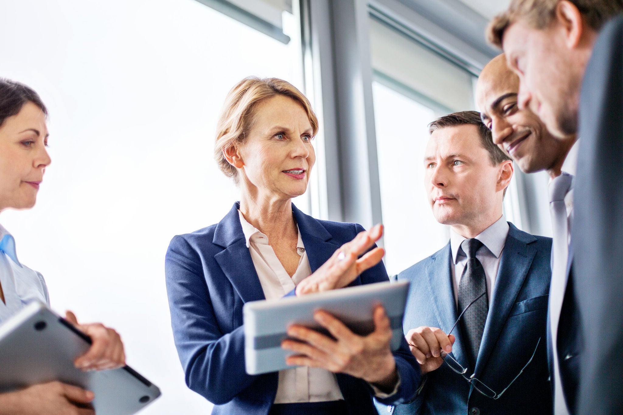 : Mature businesswoman explaining new business ideas to colleagues during a standing meeting in office