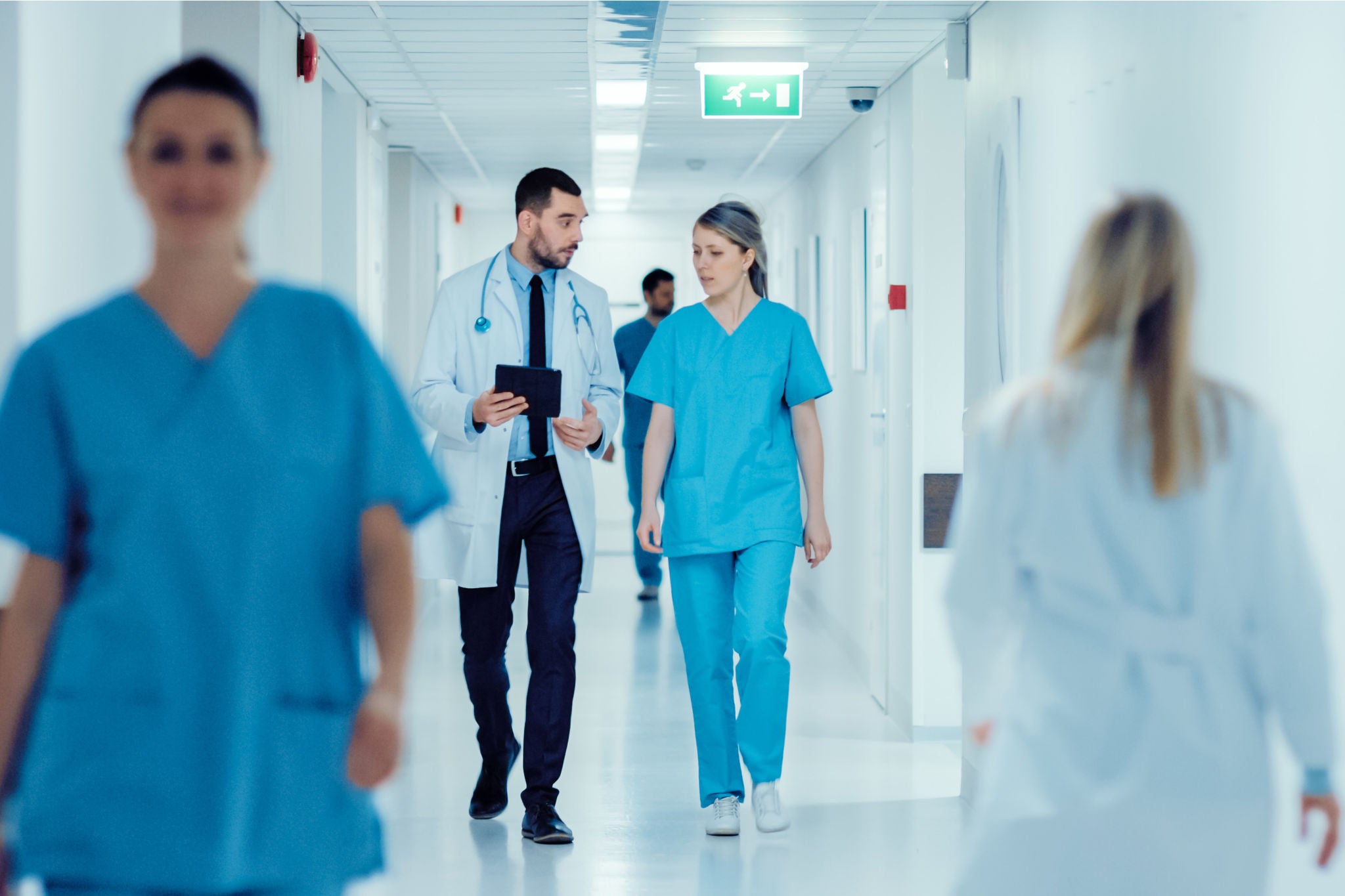 Surgeon and Female Doctor Walk Through Hospital Hallway