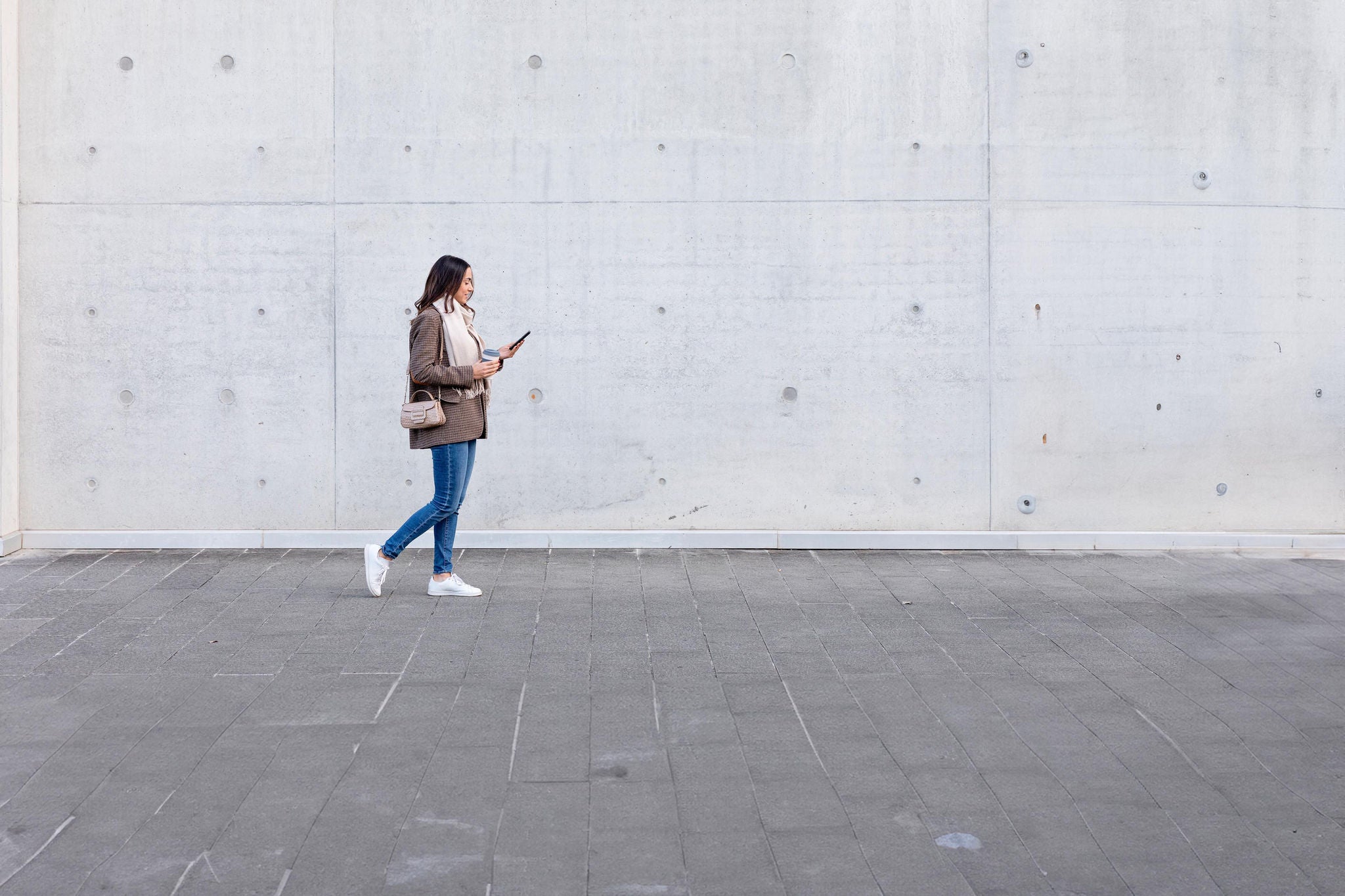 Young women with smart phone walking on foot path