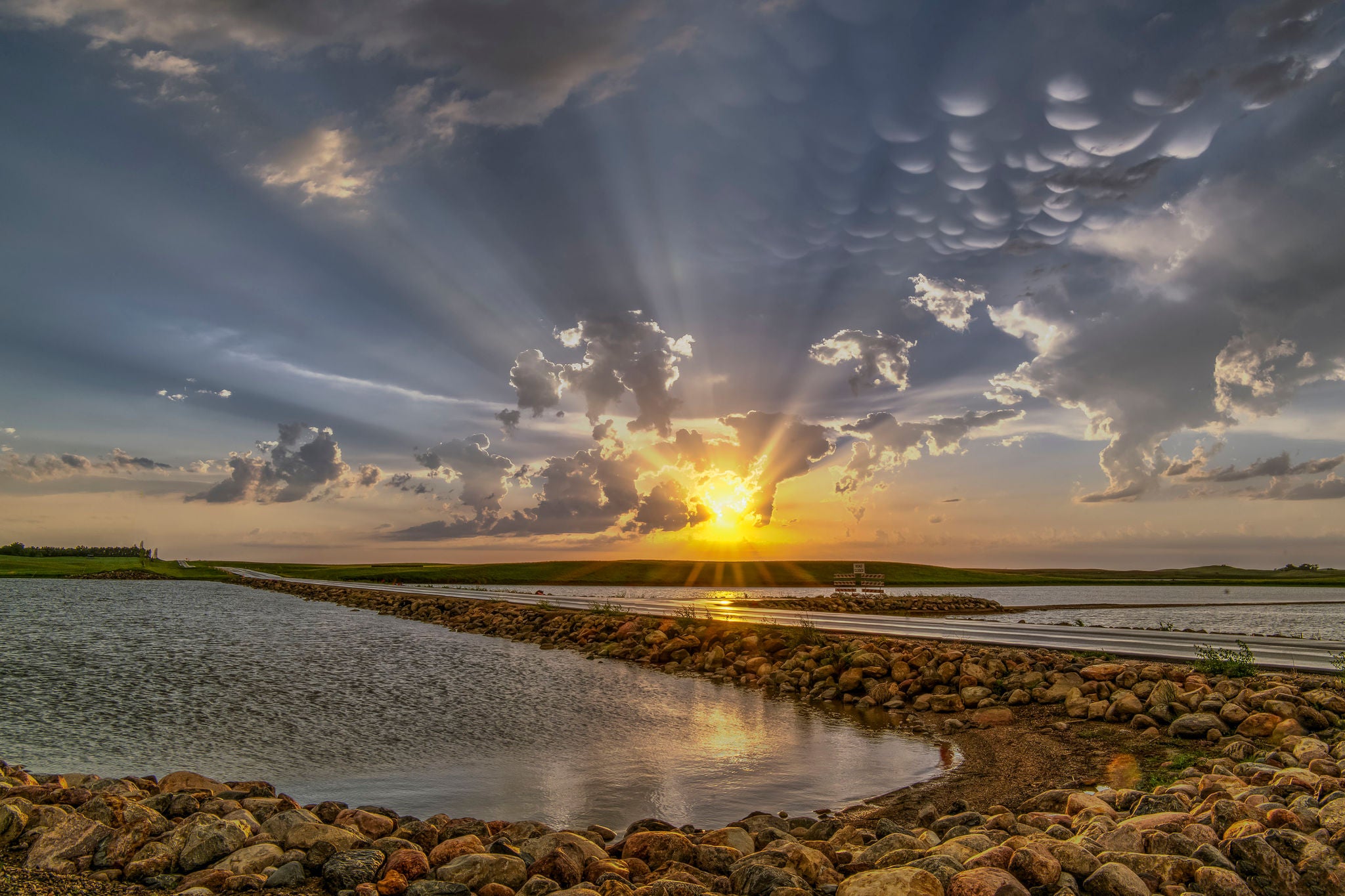 Storms on the Great Plains. Dramatic clouds, with Crepuscular Rays over a farm field on the Great Plains. Also mammatus clouds, ponds and a road.