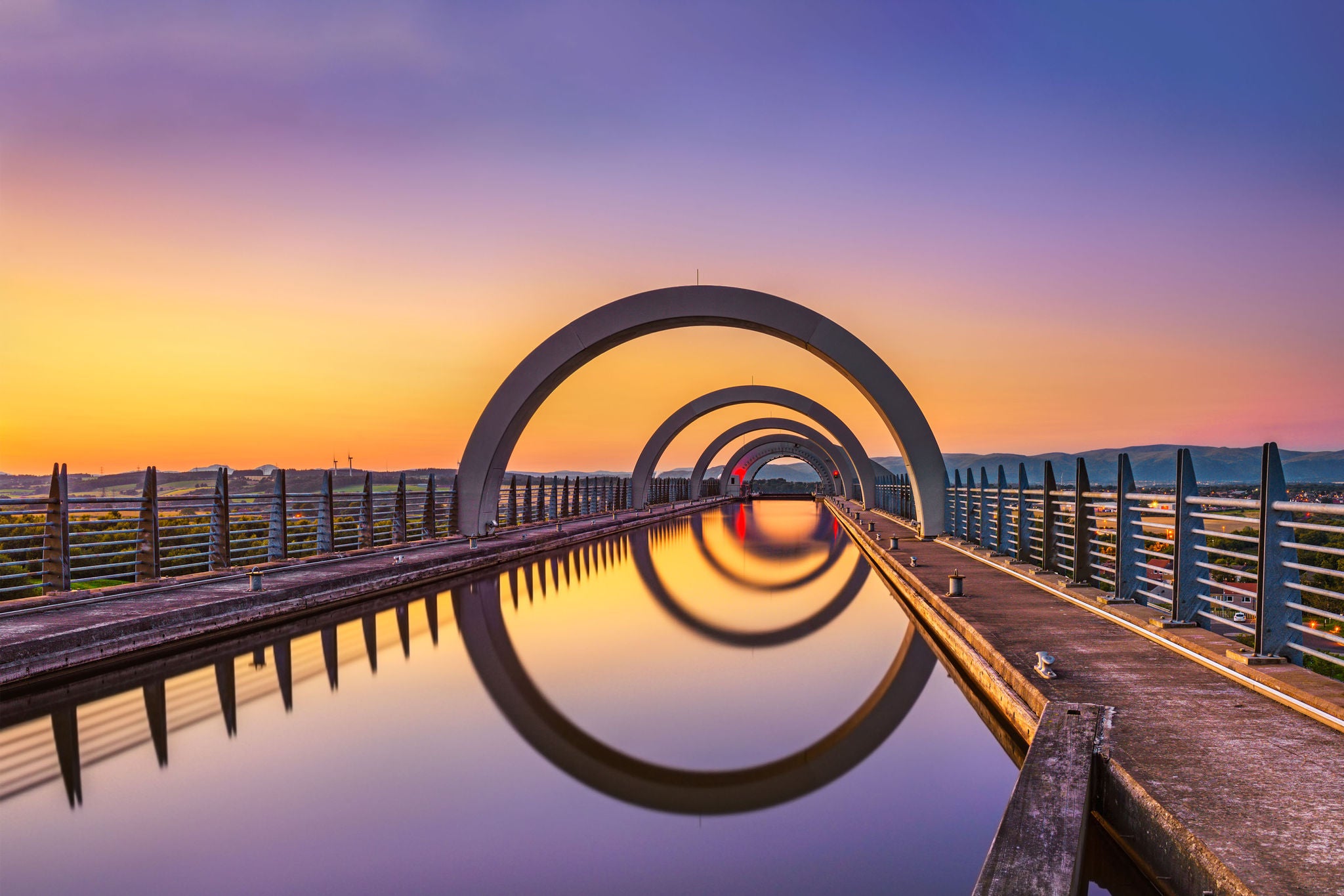 A serene sunset scene featuring a bridge, its reflection forming a perfect circle on the tranquil surface.