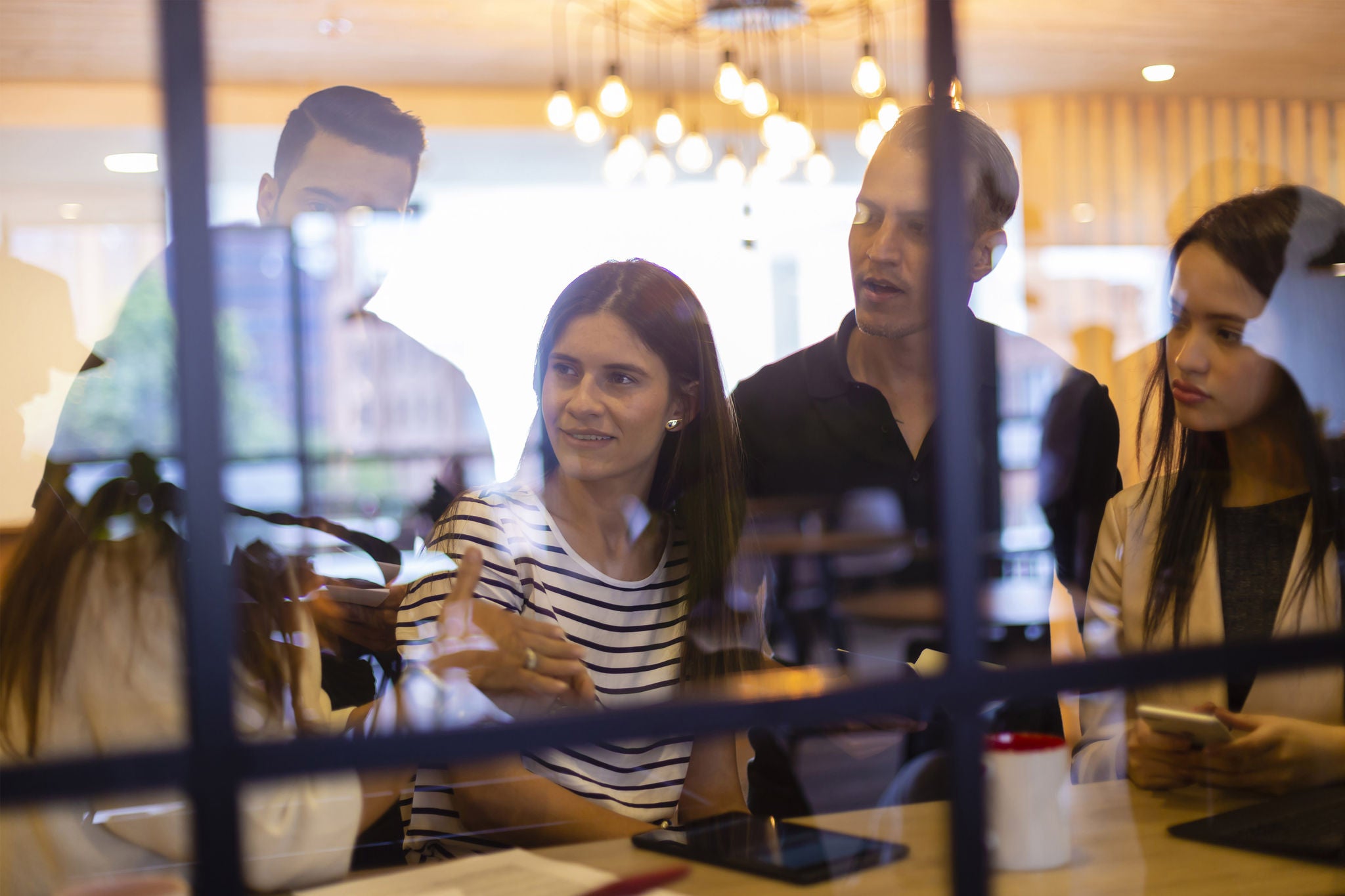 Group of people talking about some kind of work at the office while man teaching something to the thers