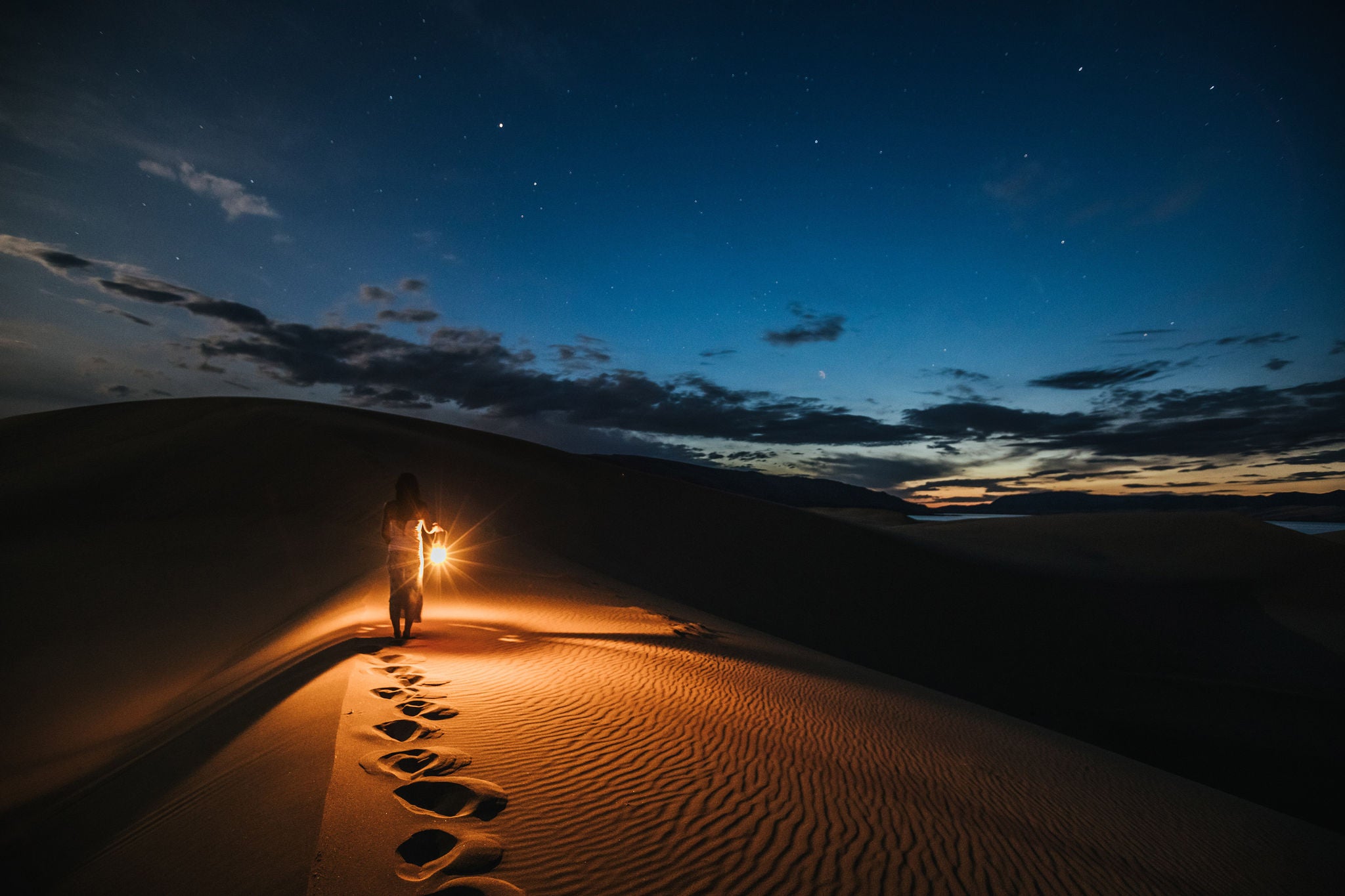 portrait of a woman with lantern walking on sand dunes at night