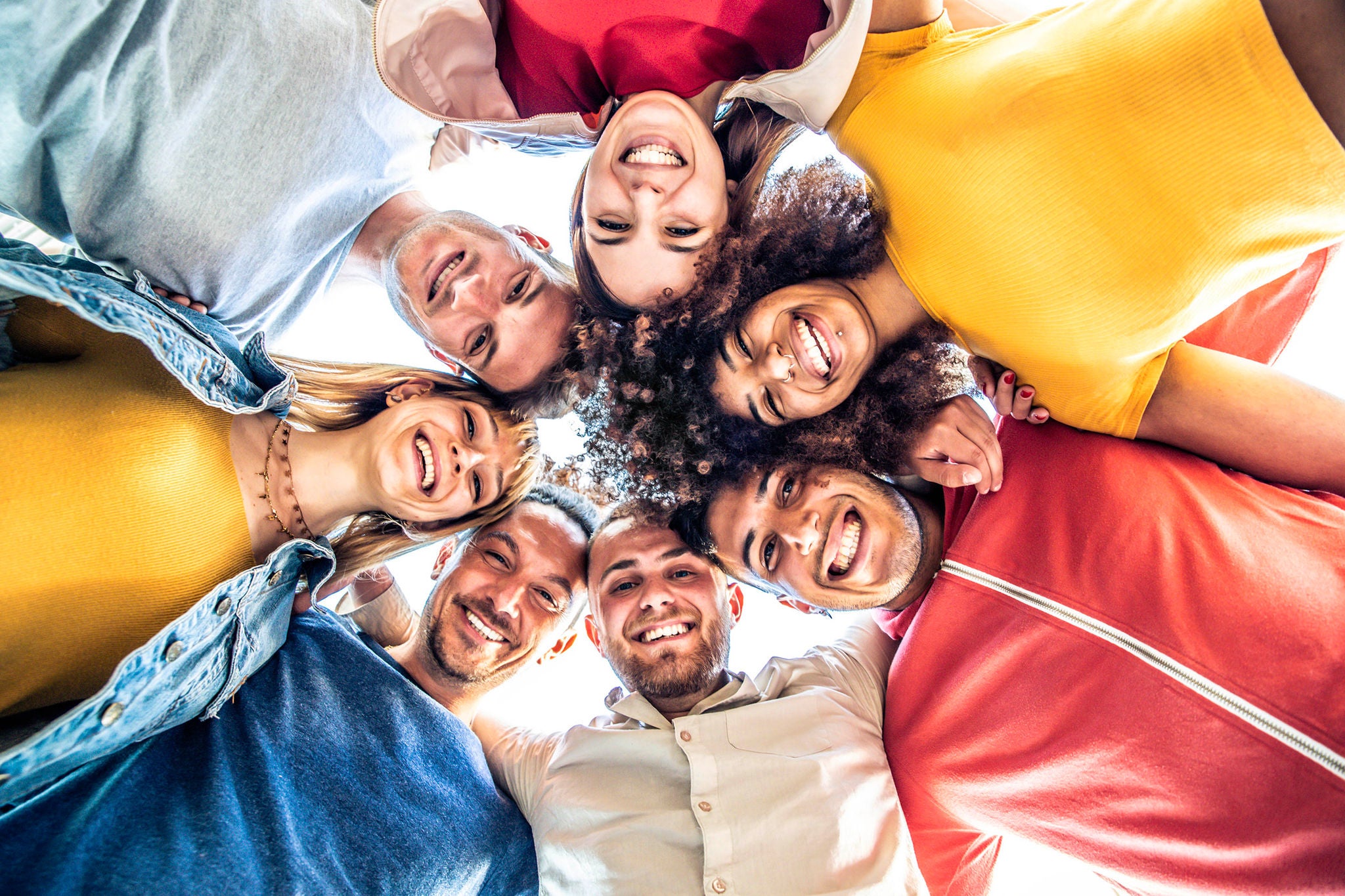 Multiracial group of young people standing in circle and smiling at camera 