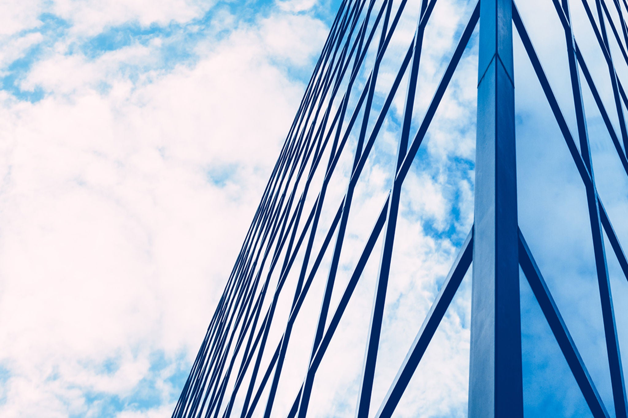 Edificio de oficinas con grandes ventanales y cielo con nubes de fondo