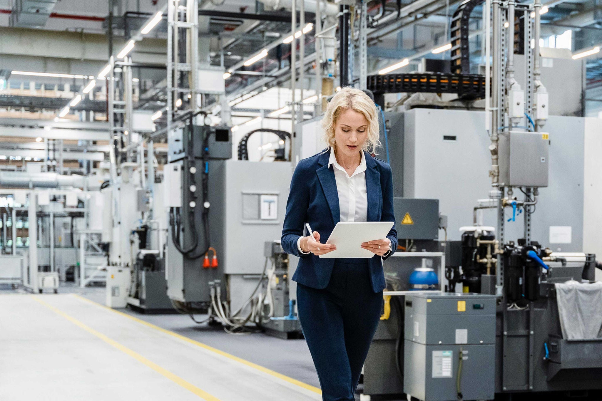 Businesswoman using tablet PC walking at modern factory