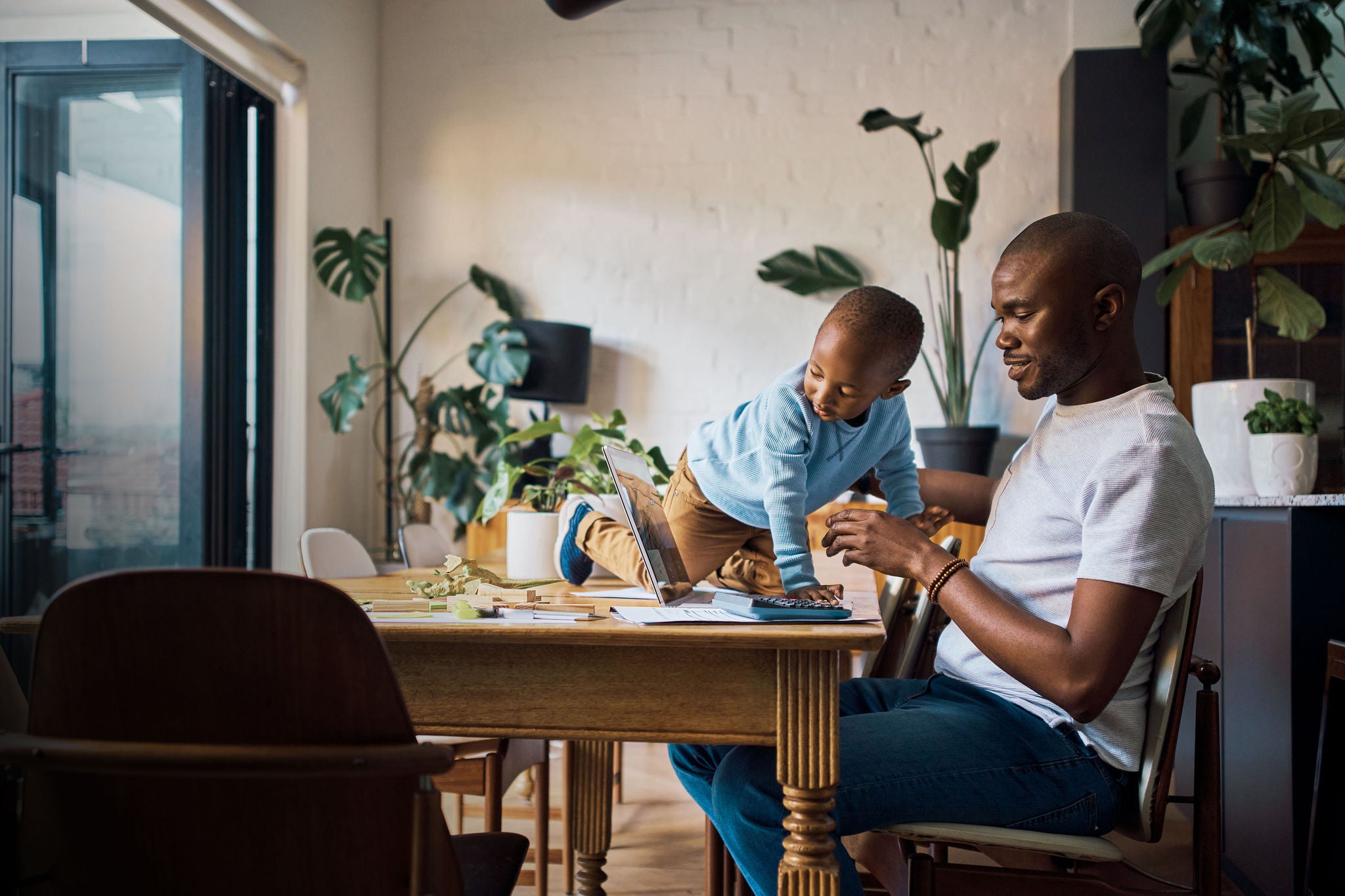 black man and son in their home together to work on finance or the budget