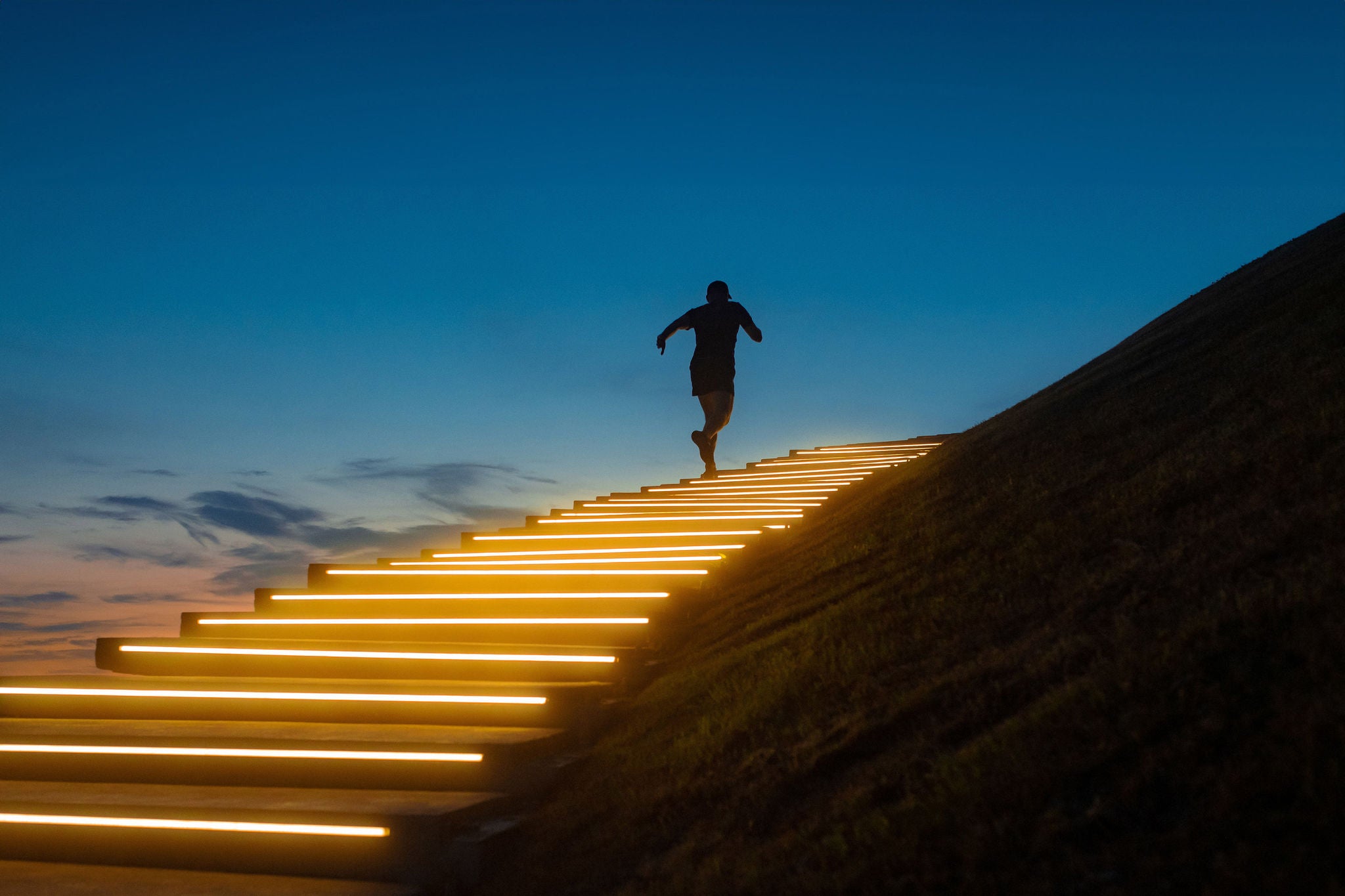 a man running a glowing staircase after sunset