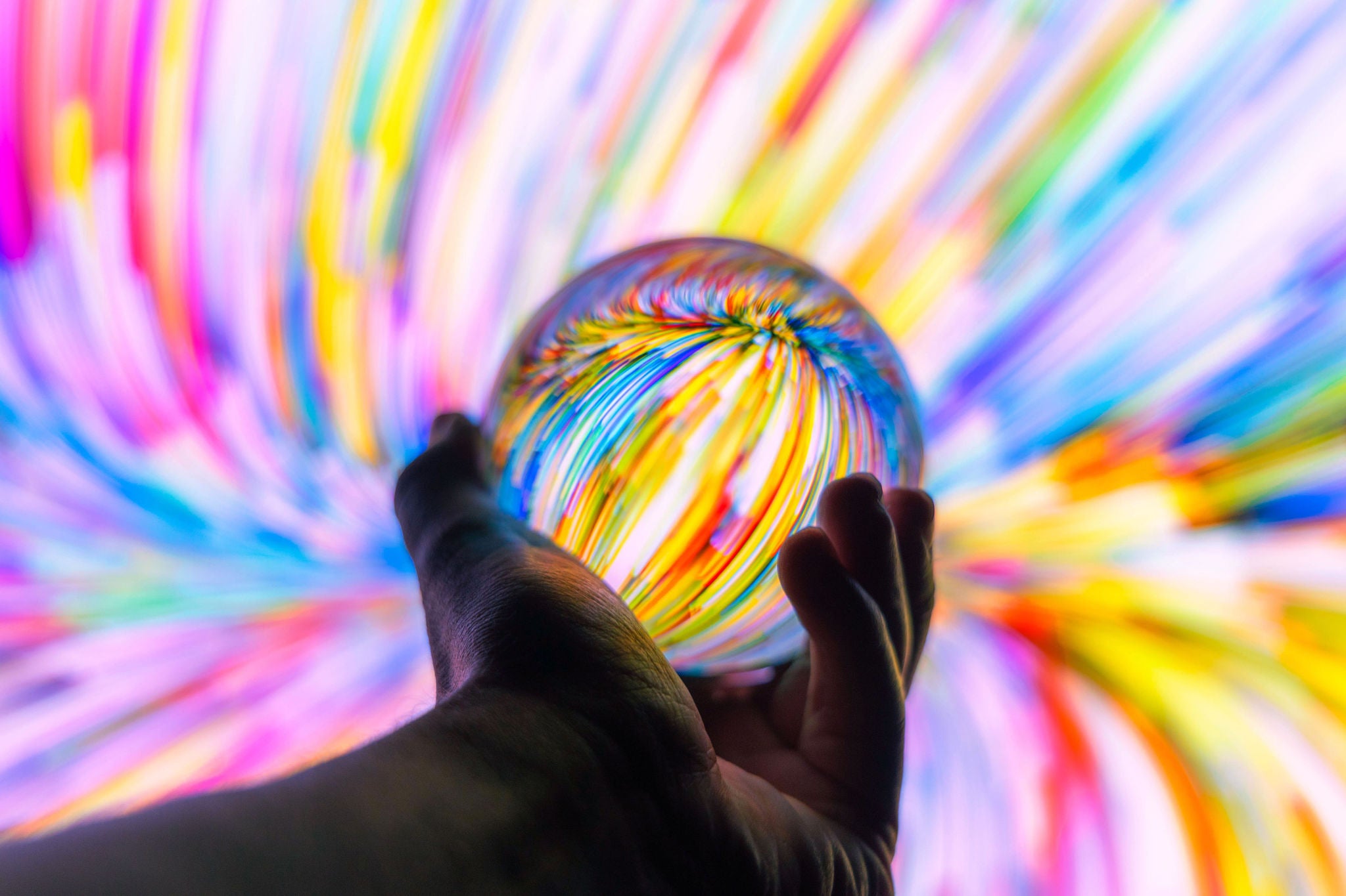 man holding a glass ball against colourfull backgroung