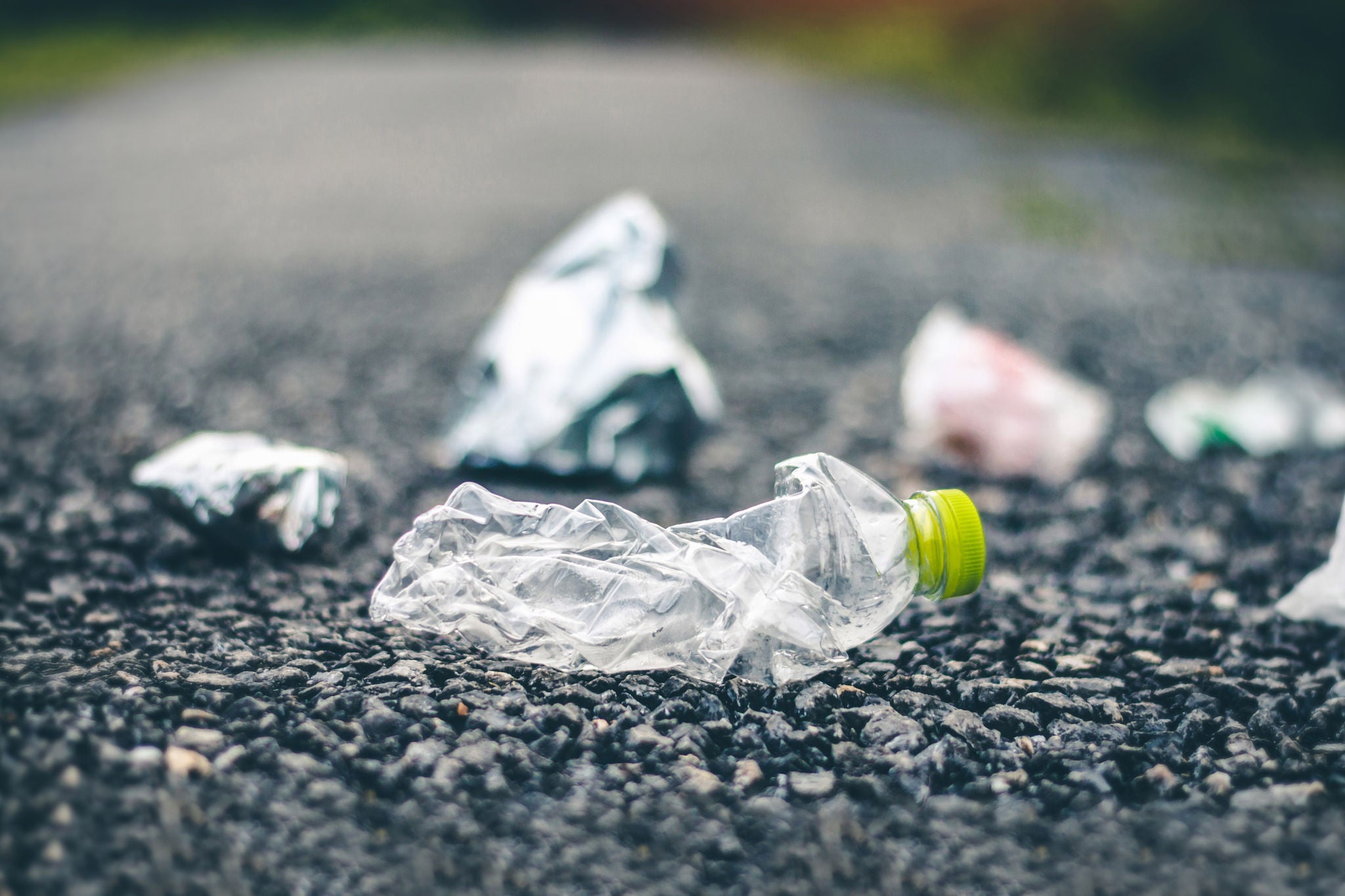 Close-up of plastic bottle and trash strewn on the road 