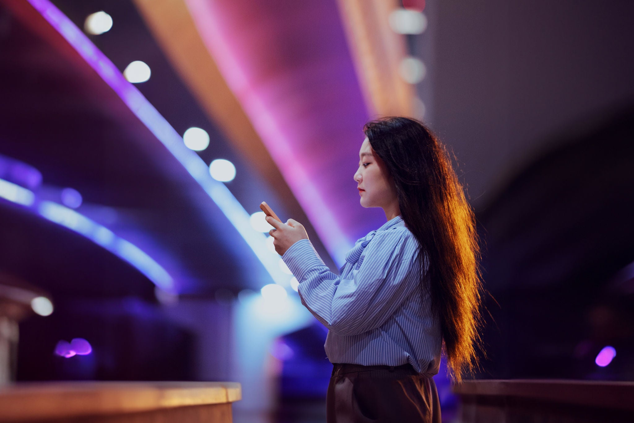 Colorful bridge at night with asian woman on the phone