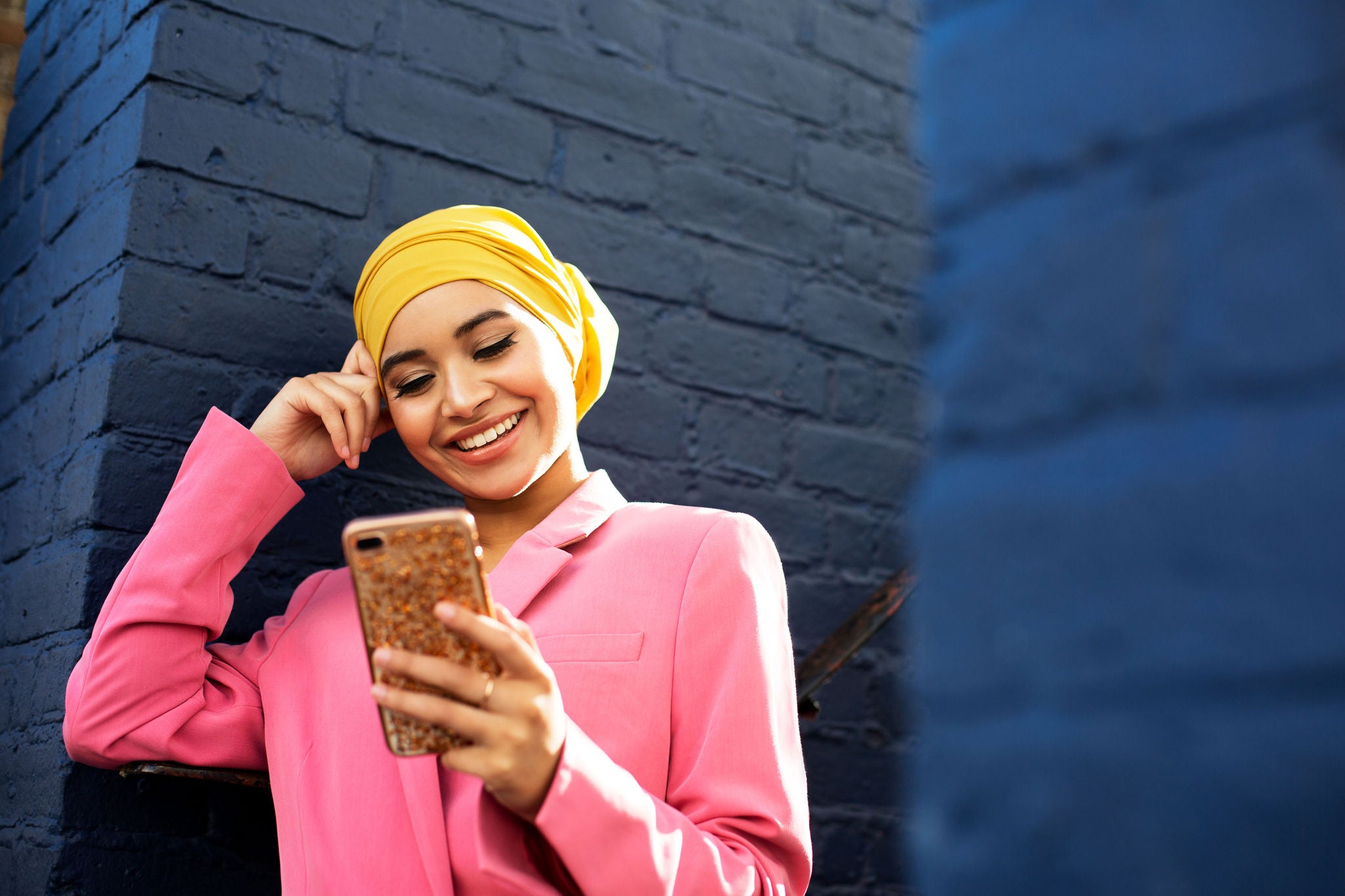 Young woman with yellow head scarf using phone